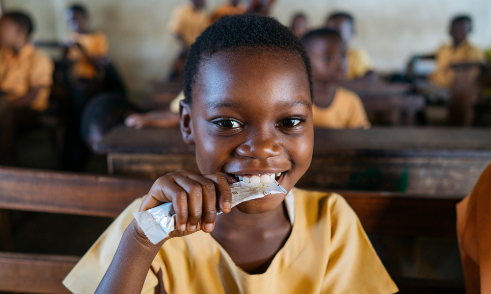 Mary Afrakomah, 7, at the Hemang Buoho D/A Primary School, Afigya Kwabre District, Ashanti Region, Ghana, holding a Vivi packet, a vitamin fortified groundnut-based snack that is provided to 50,000 school children in Ghana every day through Hershey&rsquo;s Energize Learning program.
