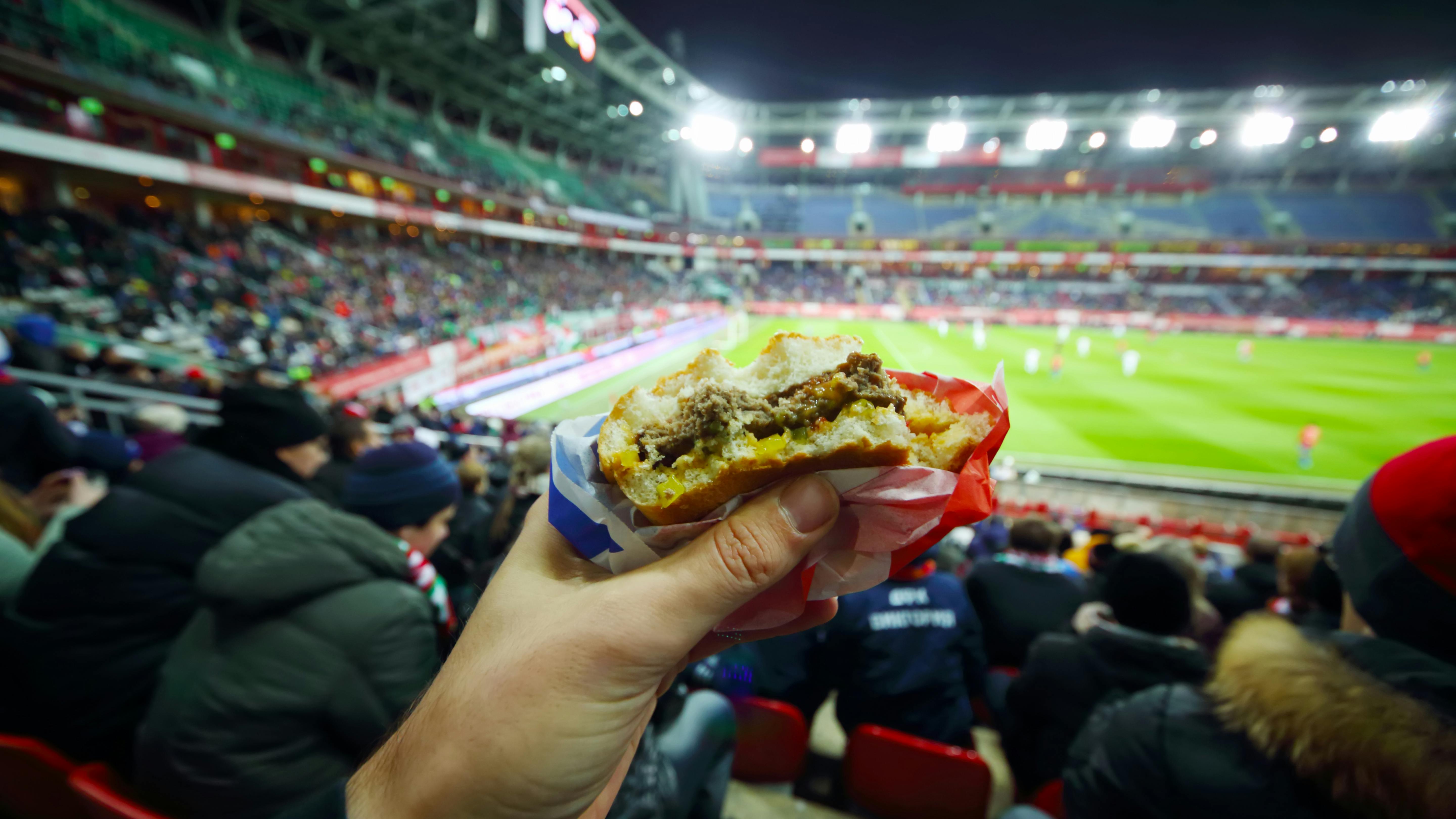 man eating hamburger in football stadium