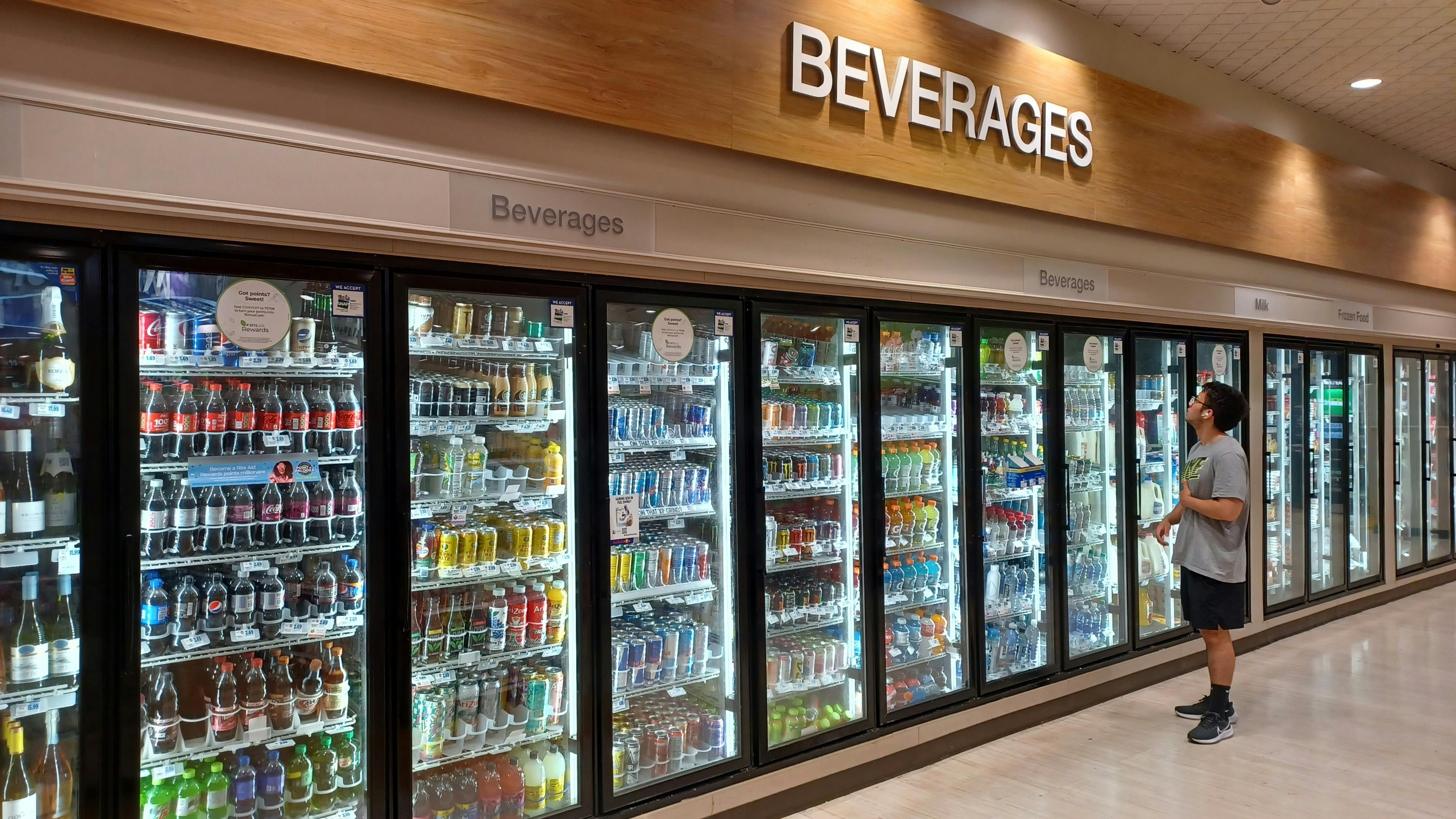 A customer looks at the drink choices in the beverage cooler in a convenience store.
