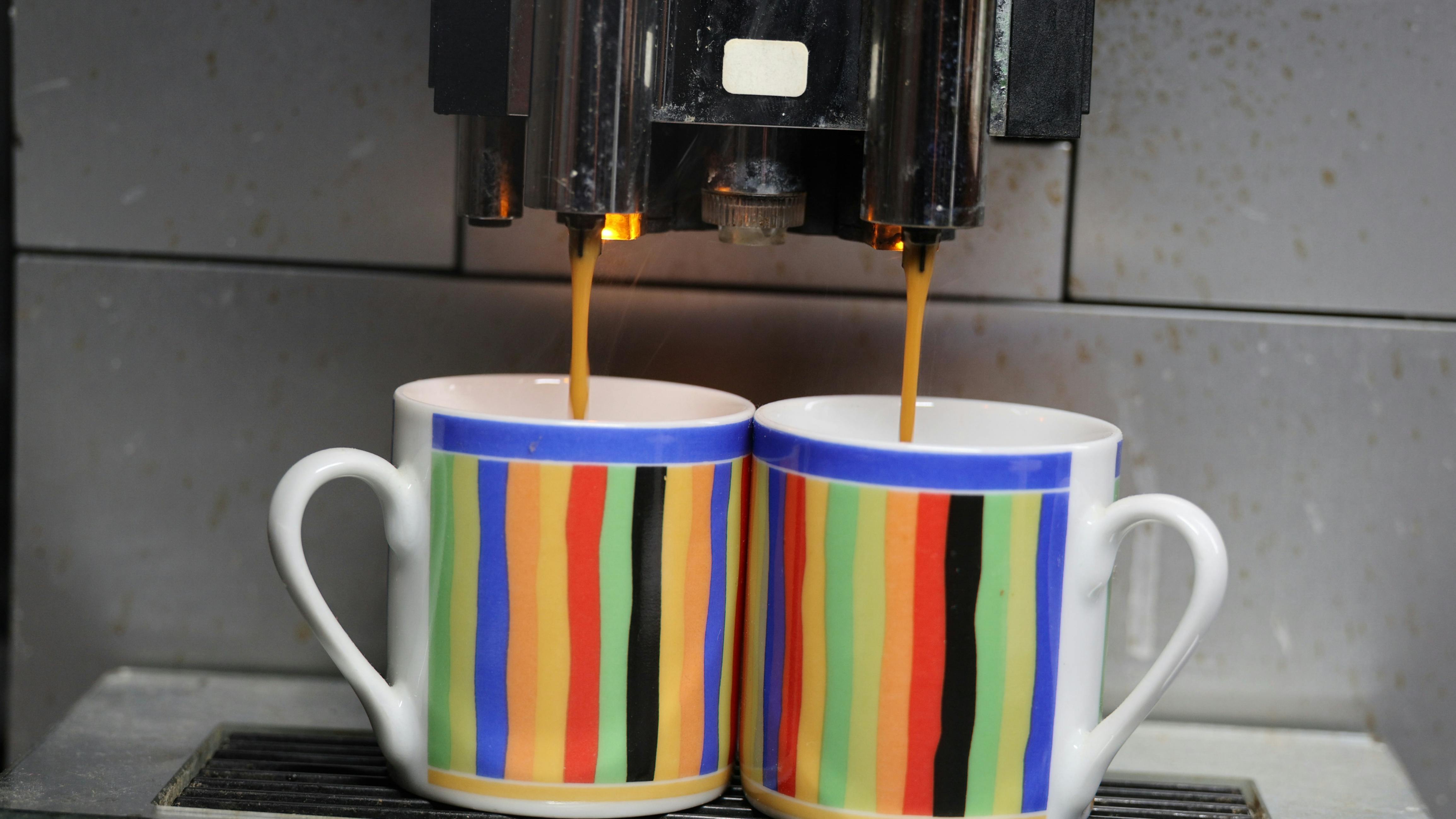 2 coffee cups filling from coffee machine dreamstime_xxl_392747280