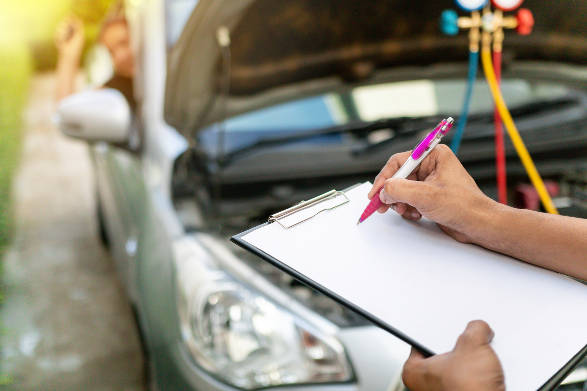 Mechanic with clipboard inspecting vehicle