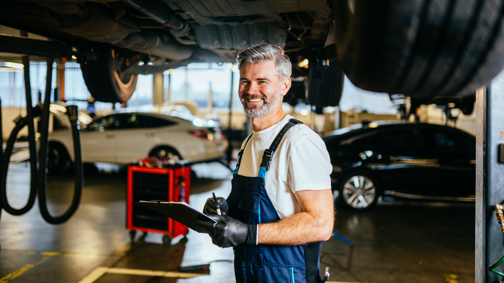 Happy automotive technician under car