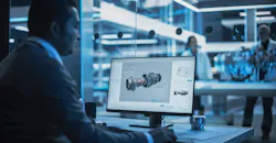 Designer working on CAD program for turbine engine, at desktop computer in plant. Designer working on CAD program for turbine engine, at desktop computer in plant.