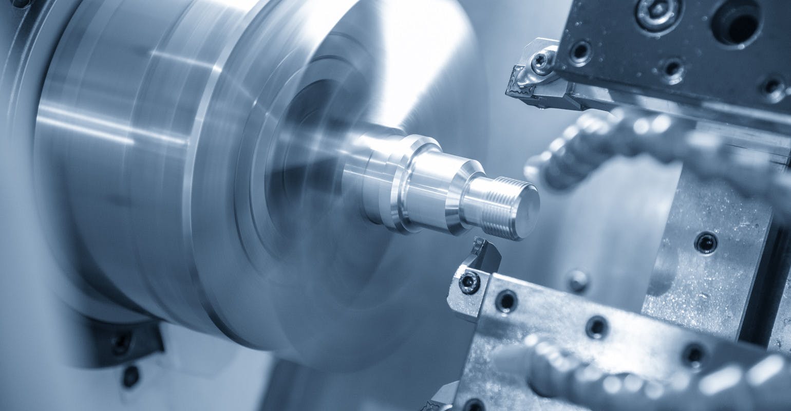 A CNC lathe machine cutting the thread at the metal parts.