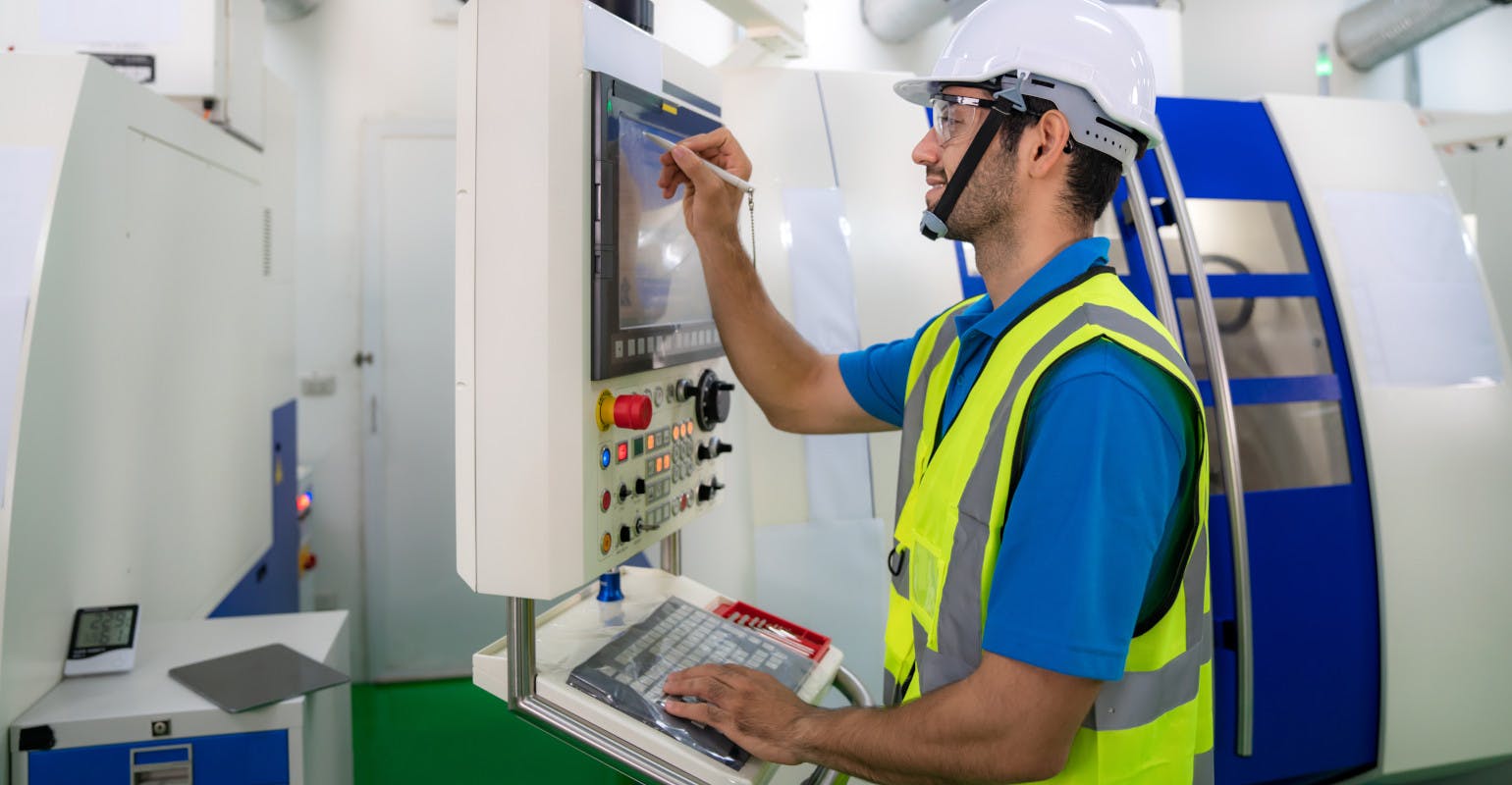 CNC operator recording data at a milling machine.