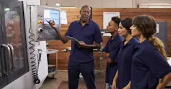 Experienced engineer training apprentices on a CNC machine Experienced engineer training apprentices on a CNC machine