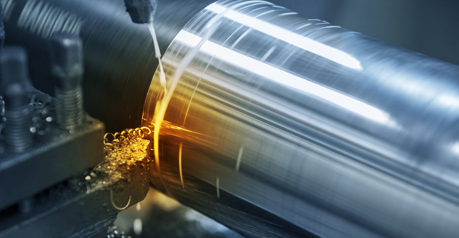 Lathe cutting of a steel rod in the light blue scene.