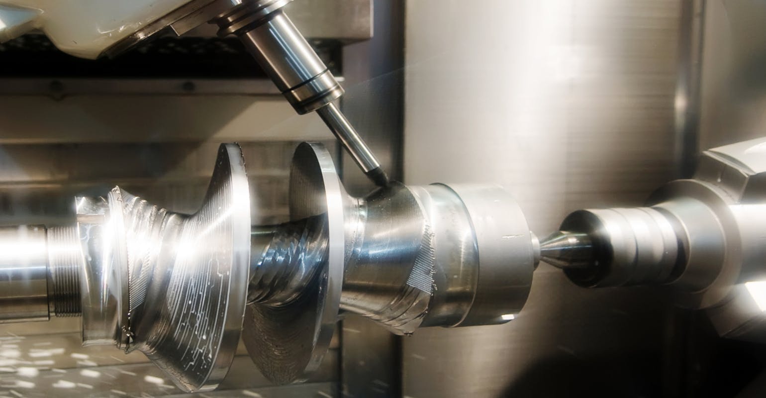 Metal workpiece being processed on a drilling machine.