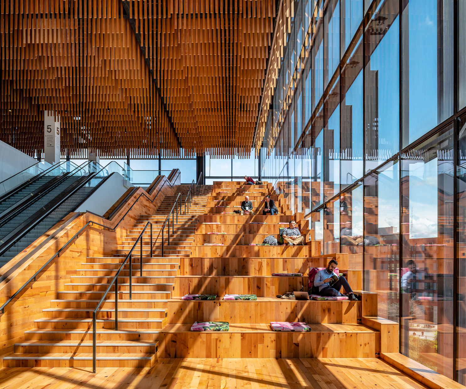 The concept for the wood ceiling above the Hill Climb stairs was inspired by the canopy of the trees in the Pacific Northwest forests, the experience of being under them and the quality of light you get when the sunlight filters through the canopies of the trees in a forest. At the hill climb, that is achieved partially from the natural light coming from the adjacent glazed fa&ccedil;ade, and at night from the vertical light fixtures placed on the walls and in-between each row of the wood &ldquo;combs.&rdquo;