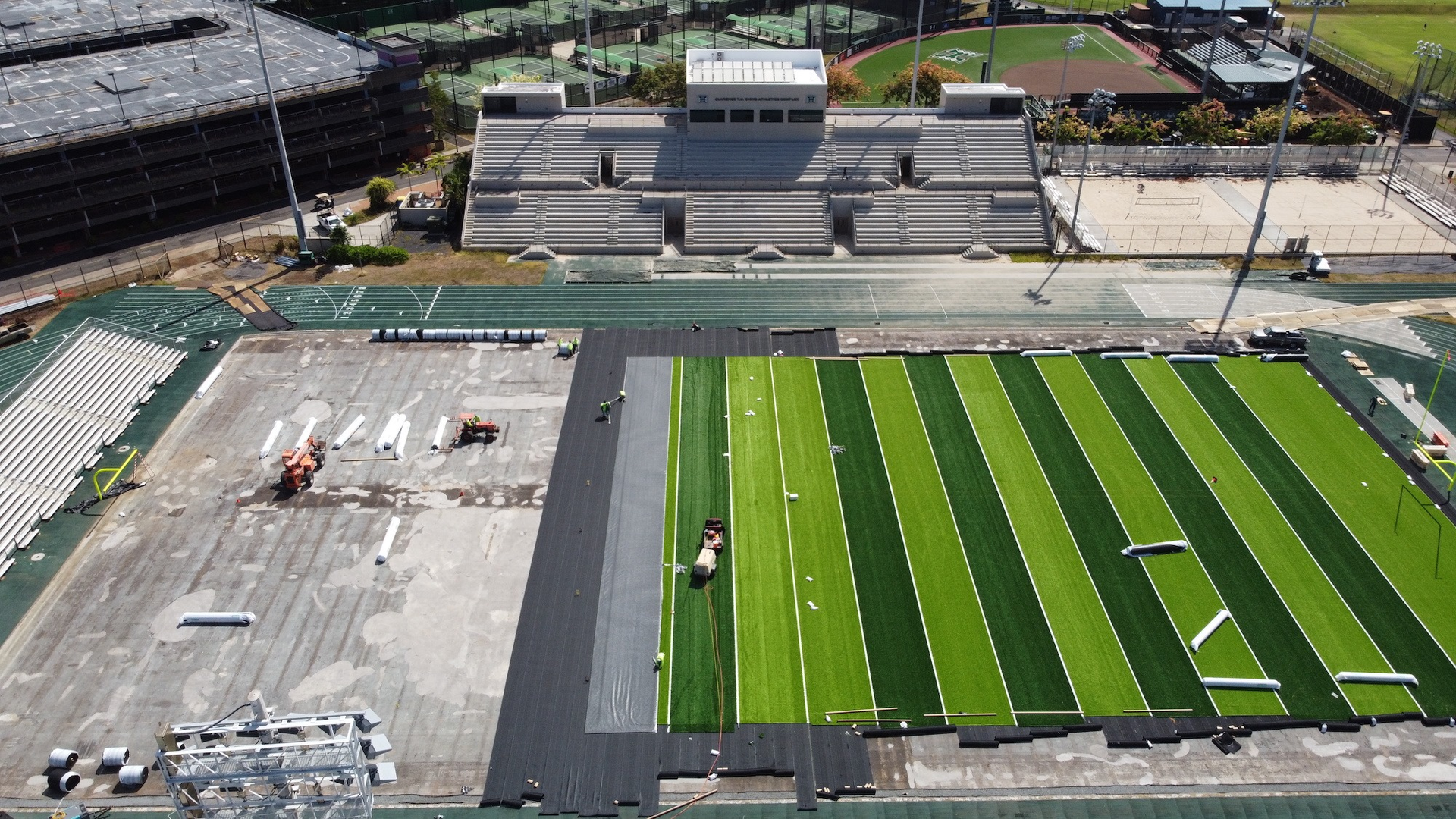 Workers install turf for the new football field at Ching Stadium