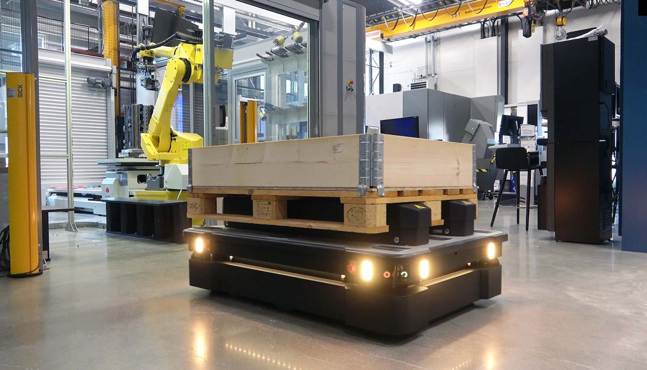 Top load mobile robot delivering pallet to robotic workcell.