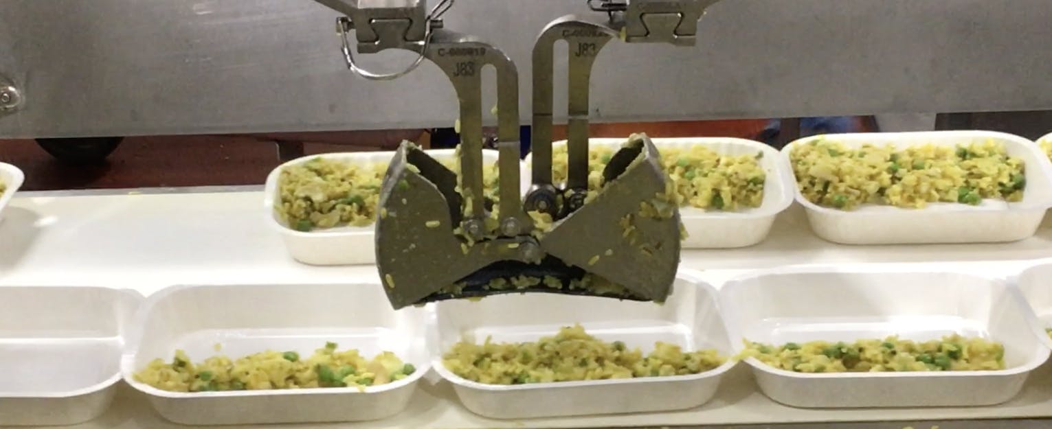 Chef Robotics' flexible automation system deposits ingredients into food trays at Amy's Kitchen. Top row of trays were filled by humans while bottom trays in foreground were filled by the Chef Robotics system. Source: Chef Robotics