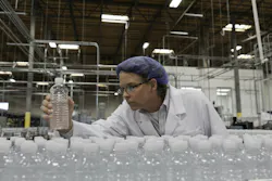 Quality control worker checking bottled water at bottling plant Quality control worker checking bottled water at bottling plant