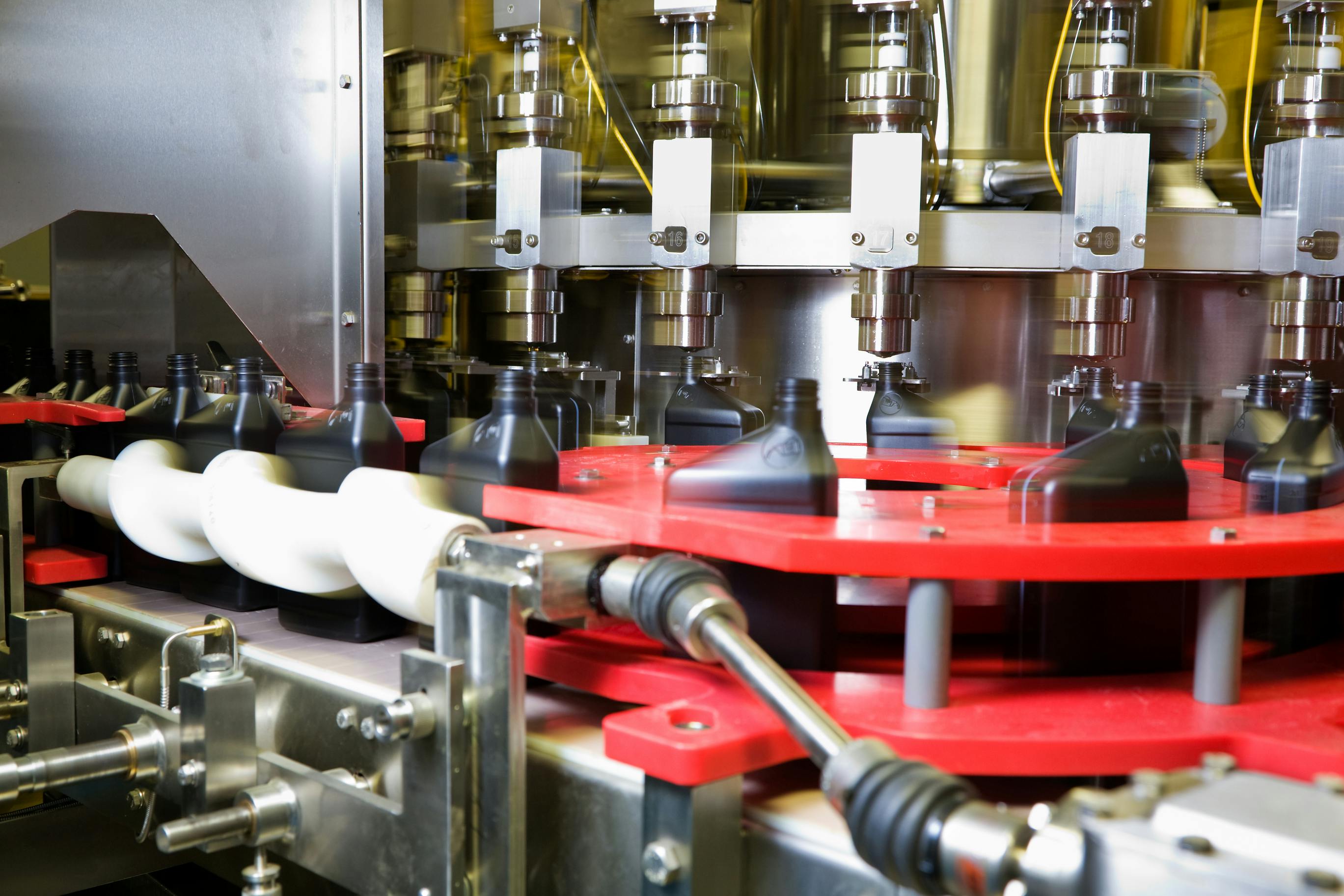 Oil dispensed on a motion controlled fill line into quart bottles at a lubricant manufacturing facility.