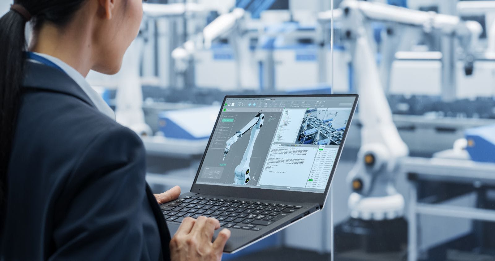 Manufacturing Robot Arms Administrator Programming Robotic Vision Systems to Execute Production at an Electronics Factory. Over the Shoulder Footage of a Female Supervising Assembly with a Computer
