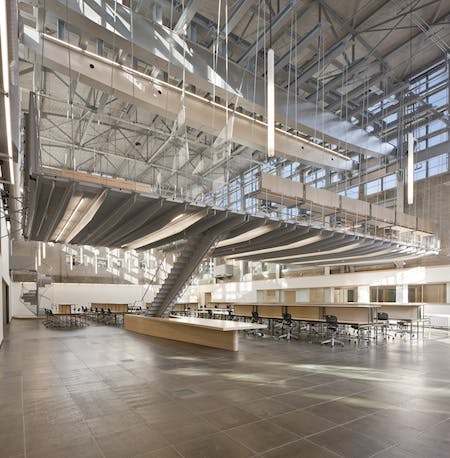 Dubbed The Hammock by students, the hanging mezzanine was created by repurposing a large bridge crane to support a tapered flo