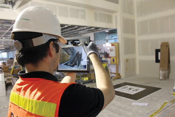 A crew member uses a ruggedized tablet equipped with augmented reality software to visualize the BIM geometry of a complex stai