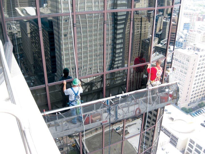 Workers repair a failed glass curtain wall. As glazed curtain walls age, many of their components may reach the end of their se