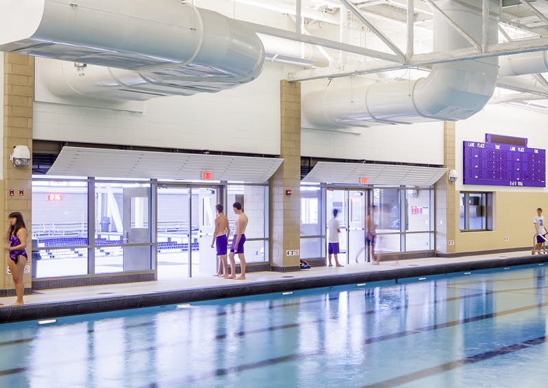 Fire-rated glass separation helps merge new and old pools into a single connected aquatics center