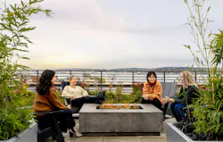 People around a modern fireplace in multifamily development People around a modern fireplace in multifamily development