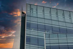 A modern glass and steel building against a colorful sunset sky. The building s facade features large windows and a grid pattern, while the sky is a blend of orange, purple, and blue A modern glass and steel building against a colorful sunset sky. The building s facade features large windows and a grid pattern, while the sky is a blend of orange, purple, and blue