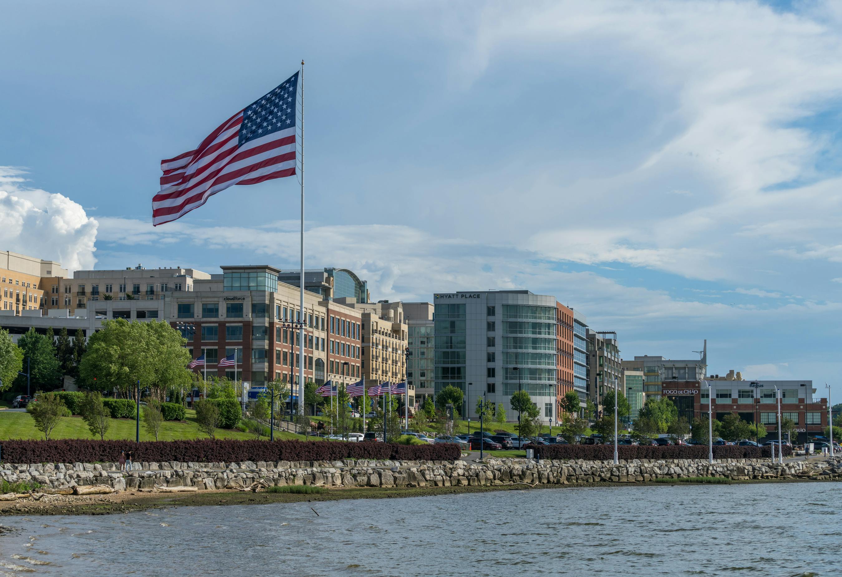 USA Flag flying at National Harbor in Maryland near Washington DC. National Harbor, MD - 24 June 2023: Skyline of National Harbor with large USA Flag flying near Washington DC