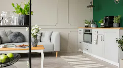 Empty green wall with copy space in elegant kitchen with white furniture,plants and coffee machine in stylish small micro-apartment with grey couch Empty green wall with copy space in elegant kitchen with white furniture,plants and coffee machine in stylish small micro-apartment with grey couch