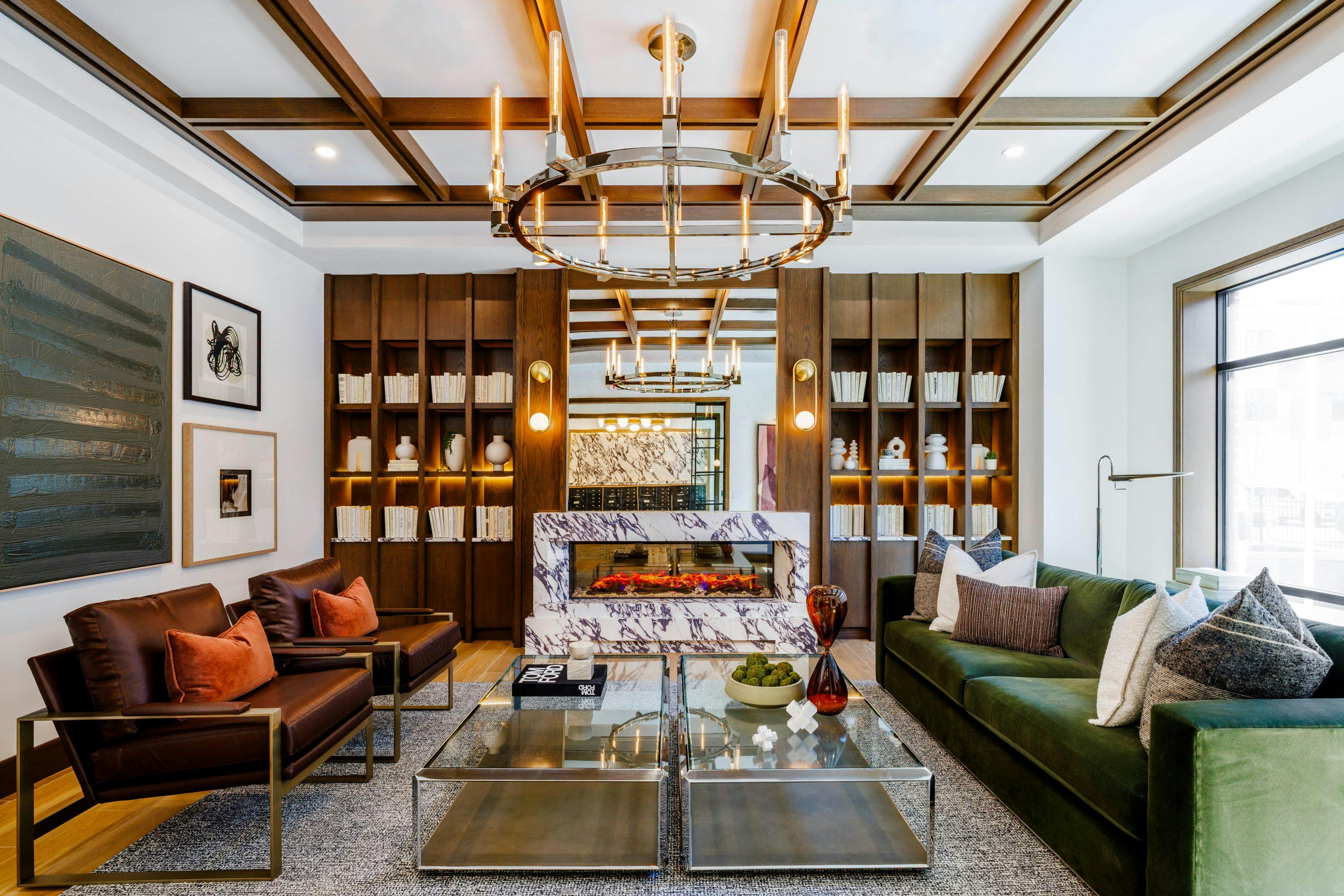 A stone fireplace anchors the resident club room at 619 North, where layered textures, warm wood tones and greenery create an inviting retreat