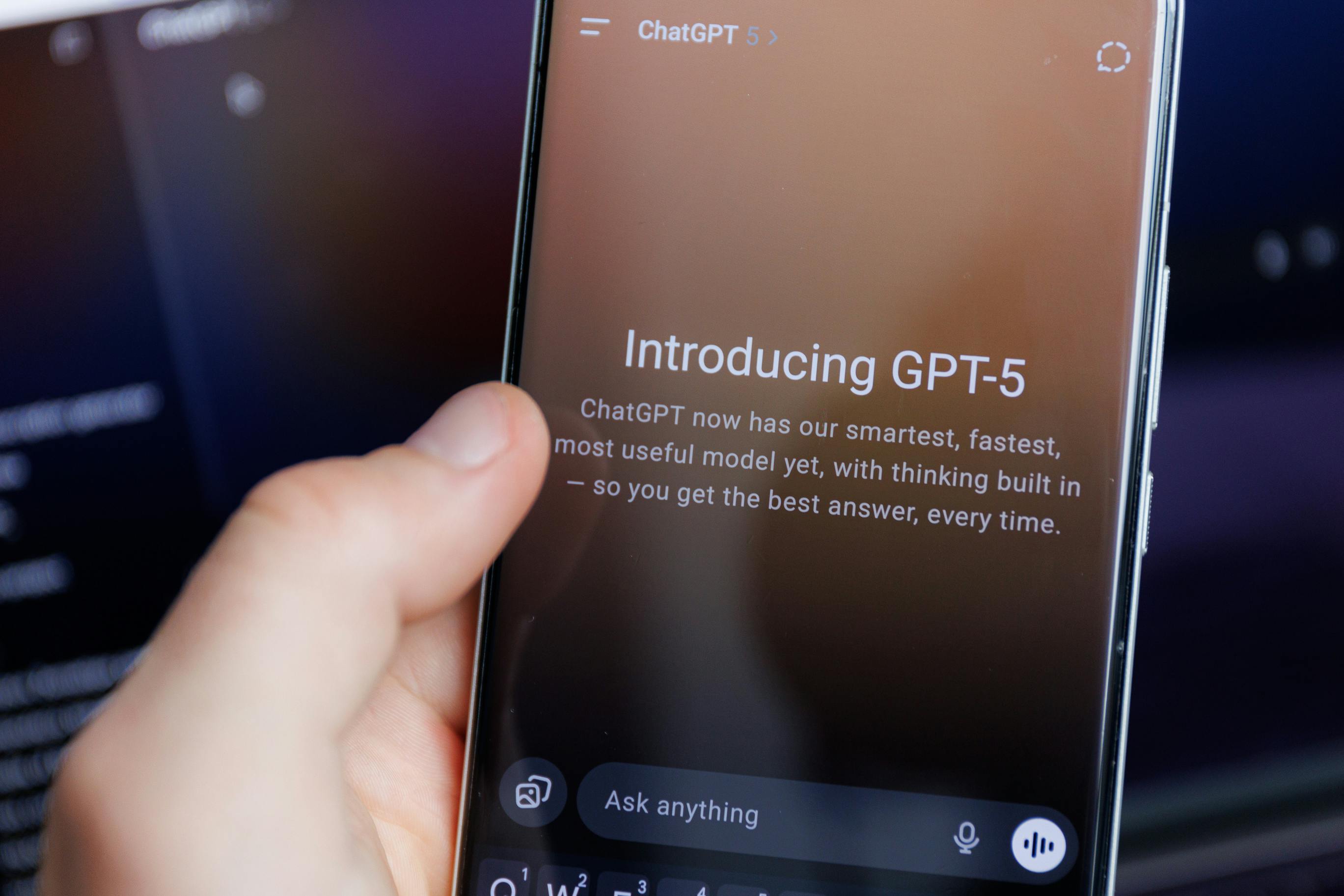Smartphone screen showing Introducing GPT-5 announcement for ChatGPT, with a hand holding the device