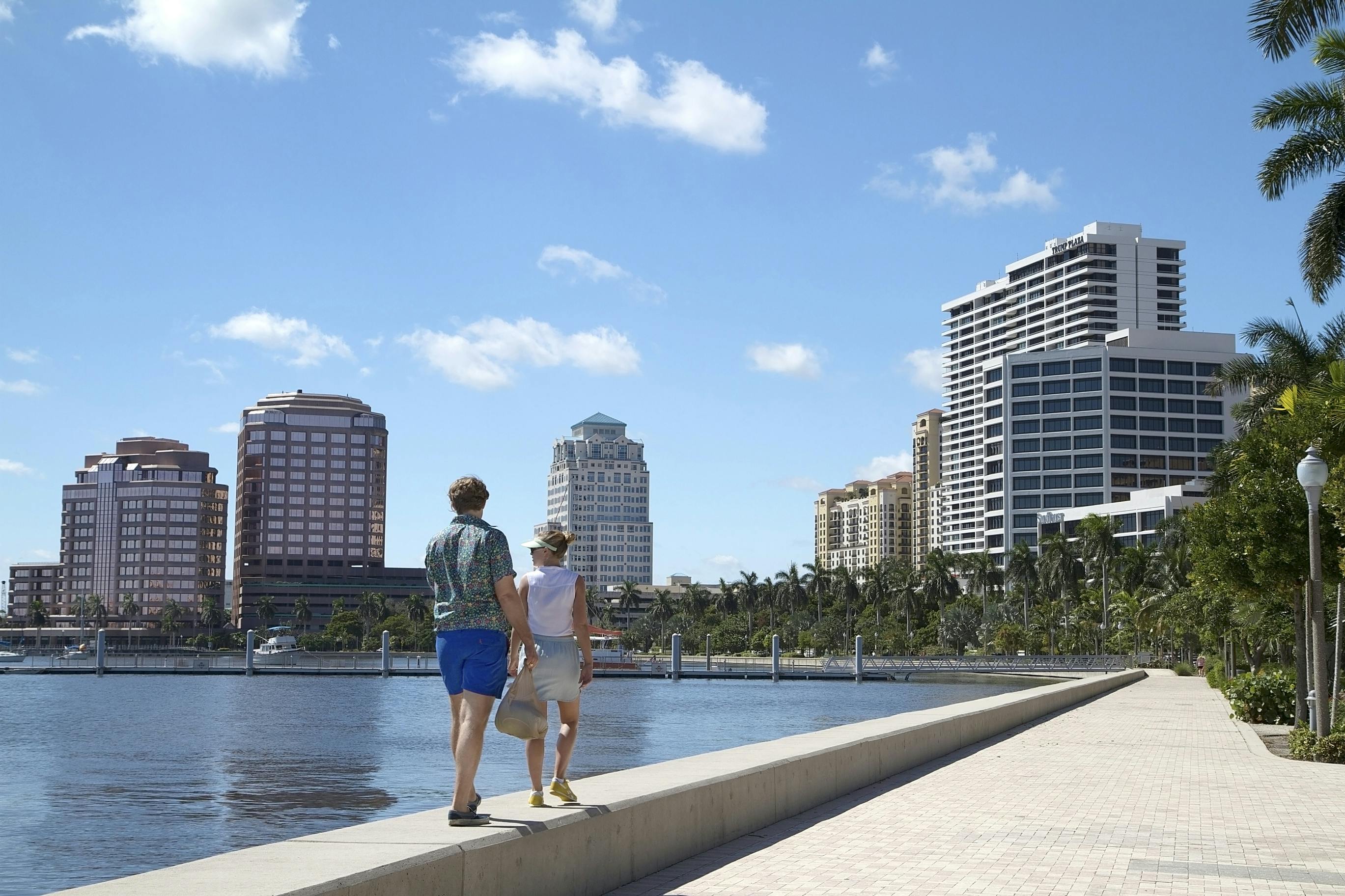 Couple enjoying the waterfront in West Palm Beach, Florida, USA. WEST PALM BEACH, FL, USA - October 3, 2015: Couple walks on the seawall at the West Palm Beach waterfront on a beautiful fall day.
