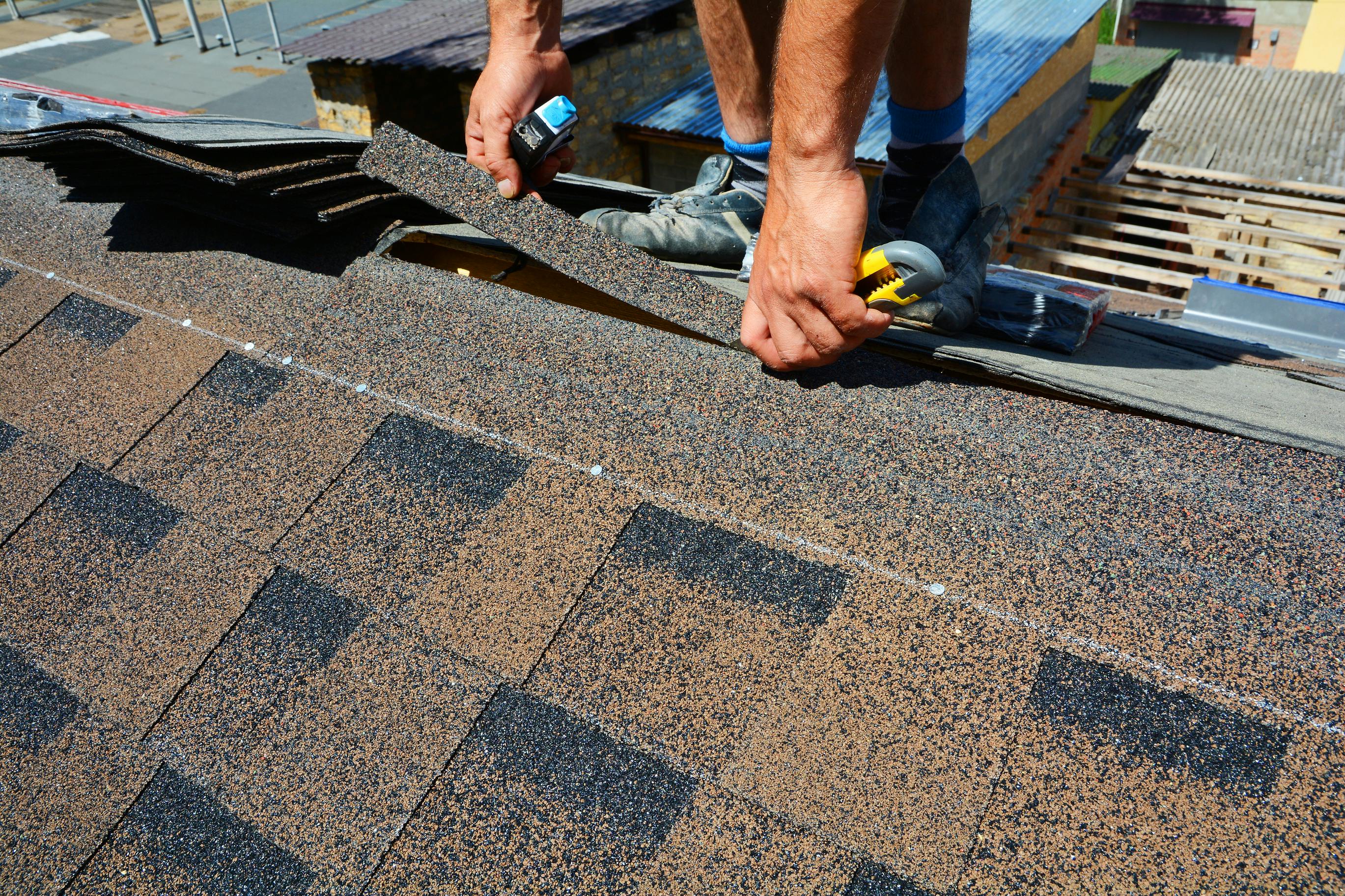 Repair of a Roofing from shingles. Roofer cutting roofing felt or bitumen during waterproofing works. Roof Shingles - Roofing. Bitumen tile roof.