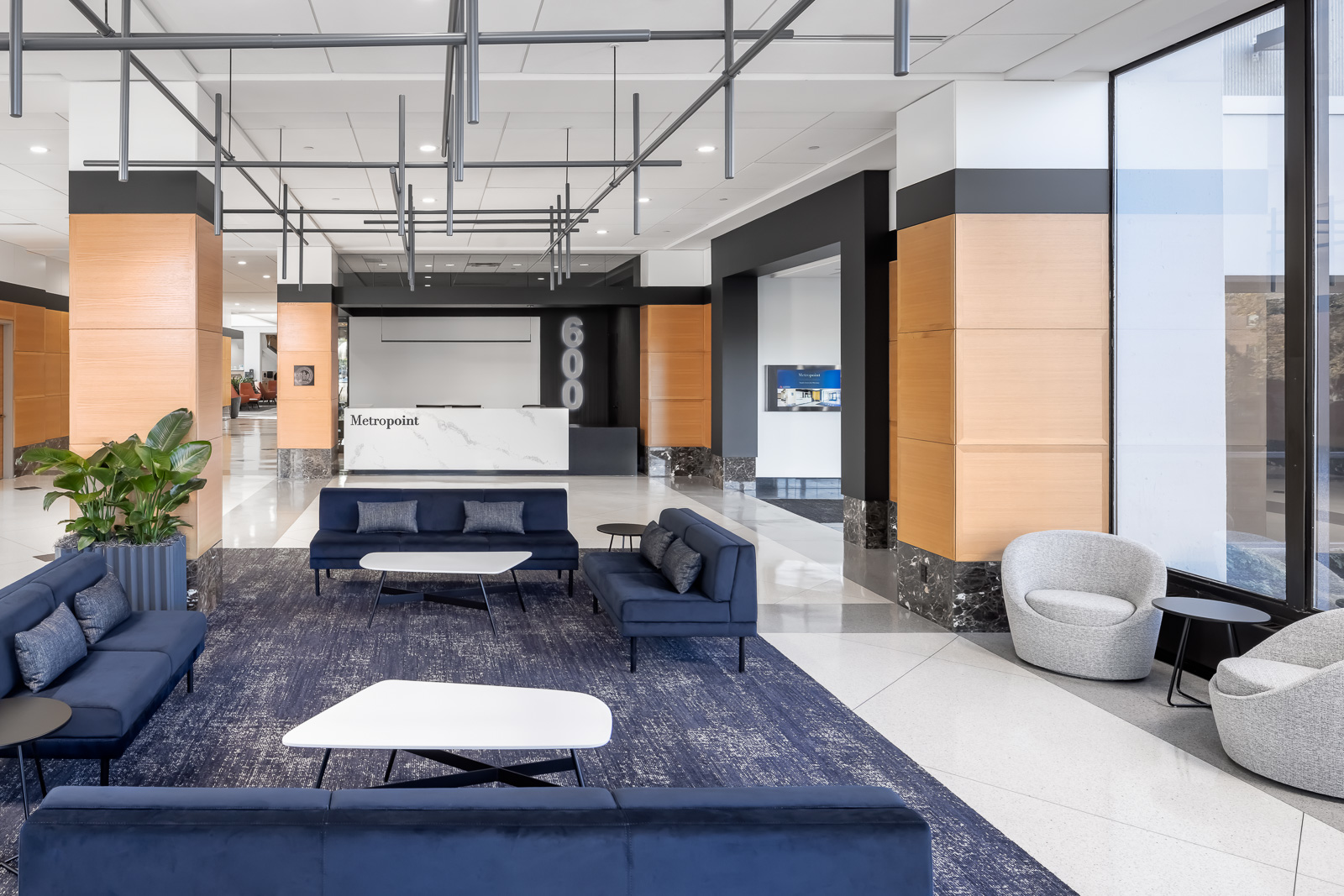 The lobby of 600 Metropoint features a strategic deployment of black and white highlights that modernizes the existing wood paneling. Comfortable seating gives guests and tenants&rsquo; employees a place to land.