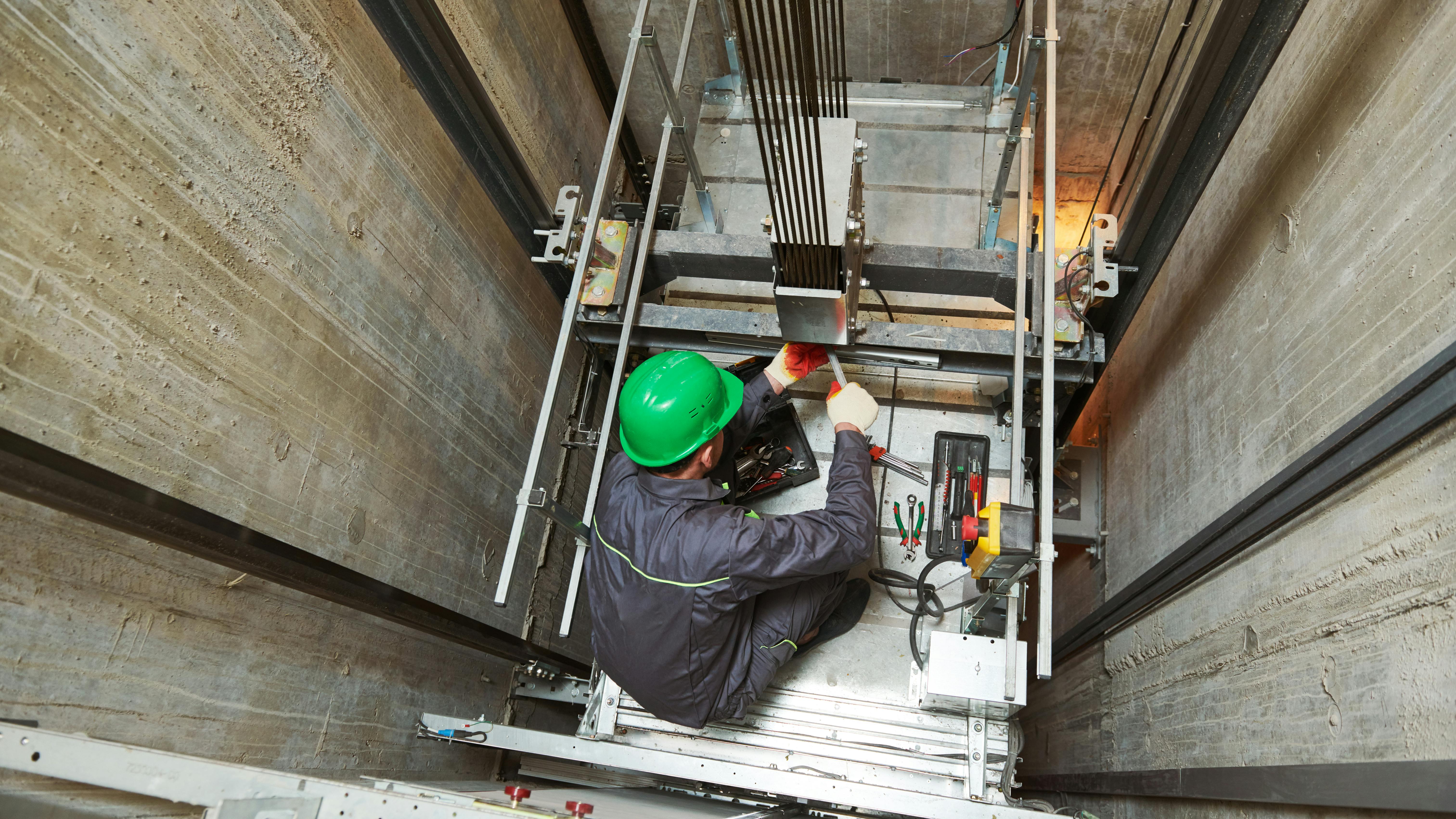 A machinist repairs an elevator in its shaft.