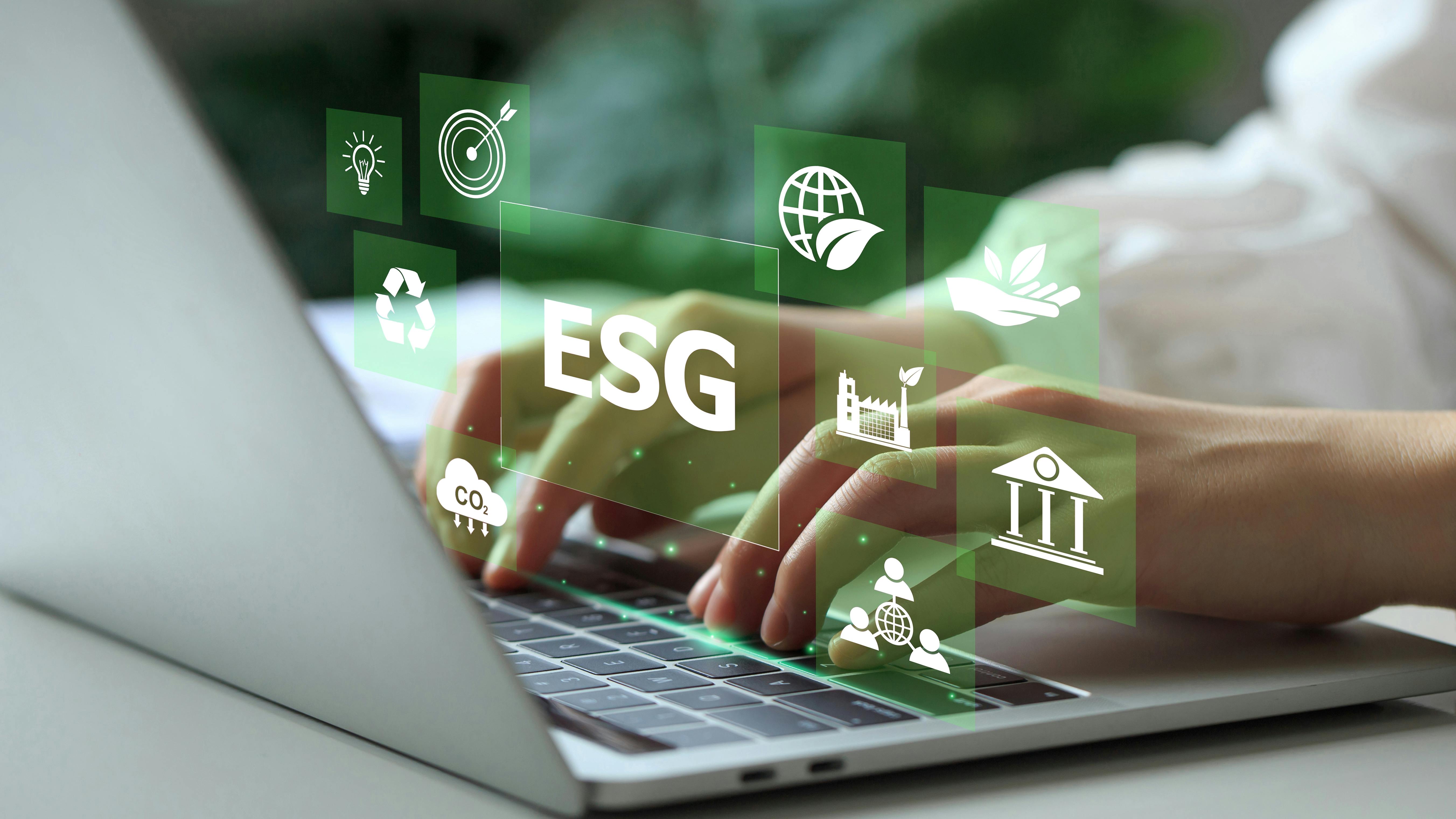 Open laptop with hands typing, overlaid with environmentally-inspired icons surrounding ESG icon.