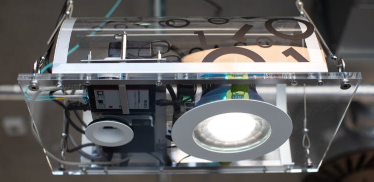 The ceiling setup at the IOP includes a fiberoptic feed (the blue cable), a Li-Fi access point (smaller disc to the left), and an LED luminaire from Lucibel. (Photo credit: Image courtesy of IOP&rsquo;s James Hopkirk.)