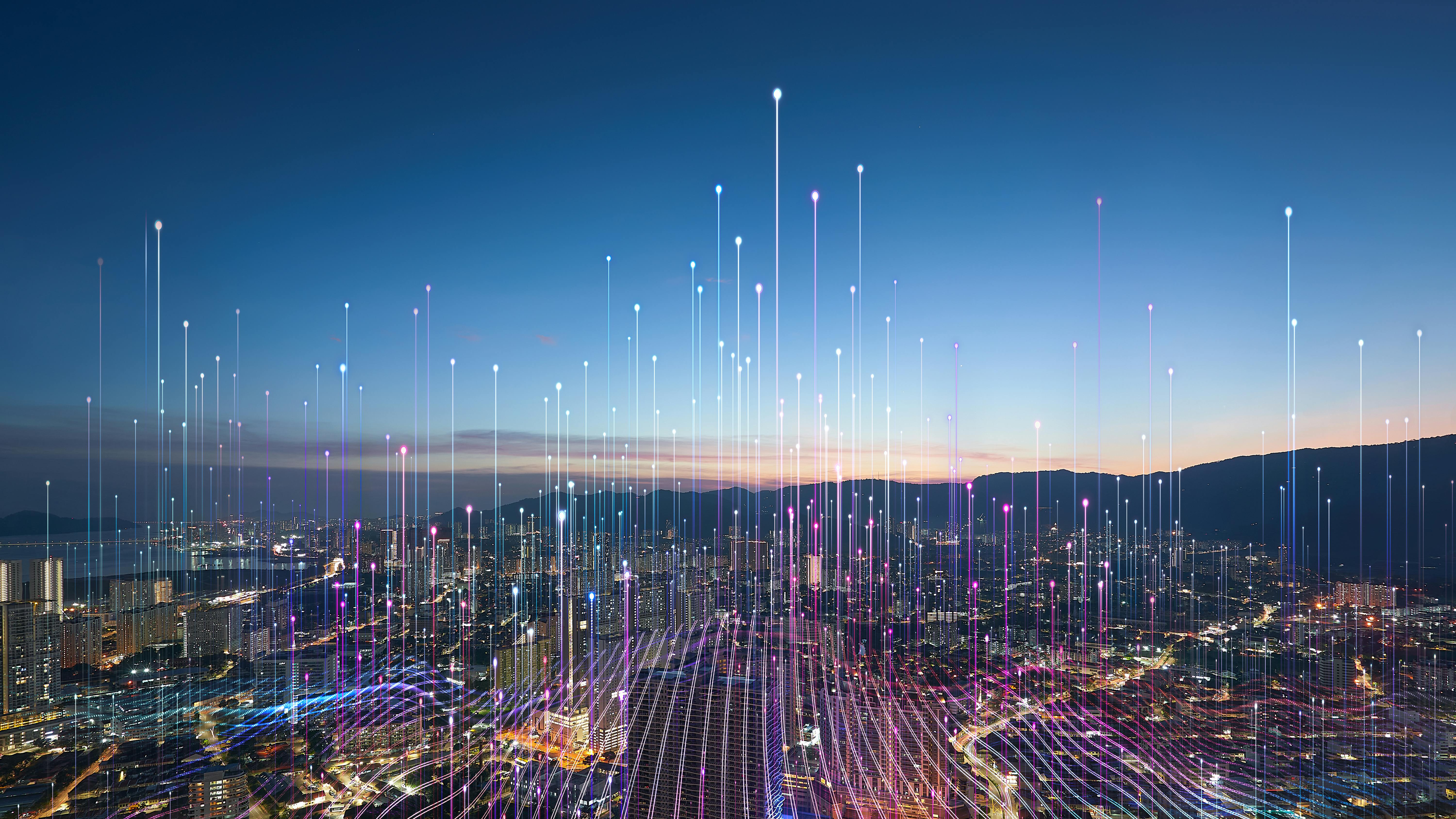 Aerial view of city at dusk with graphic overlay of tech connectivity concept.