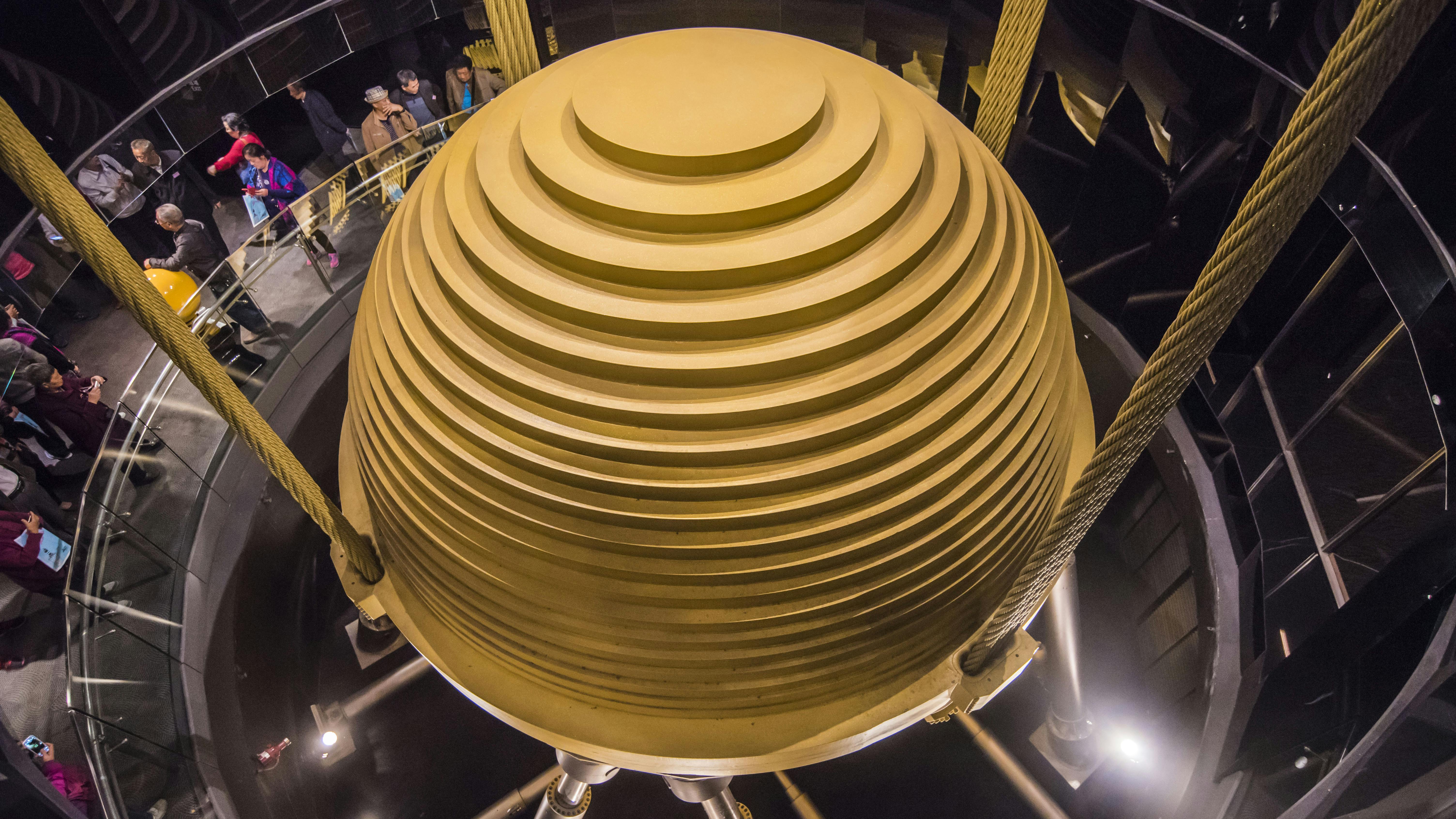 Image of massive, spherical seismic damper in building suspended by cables.