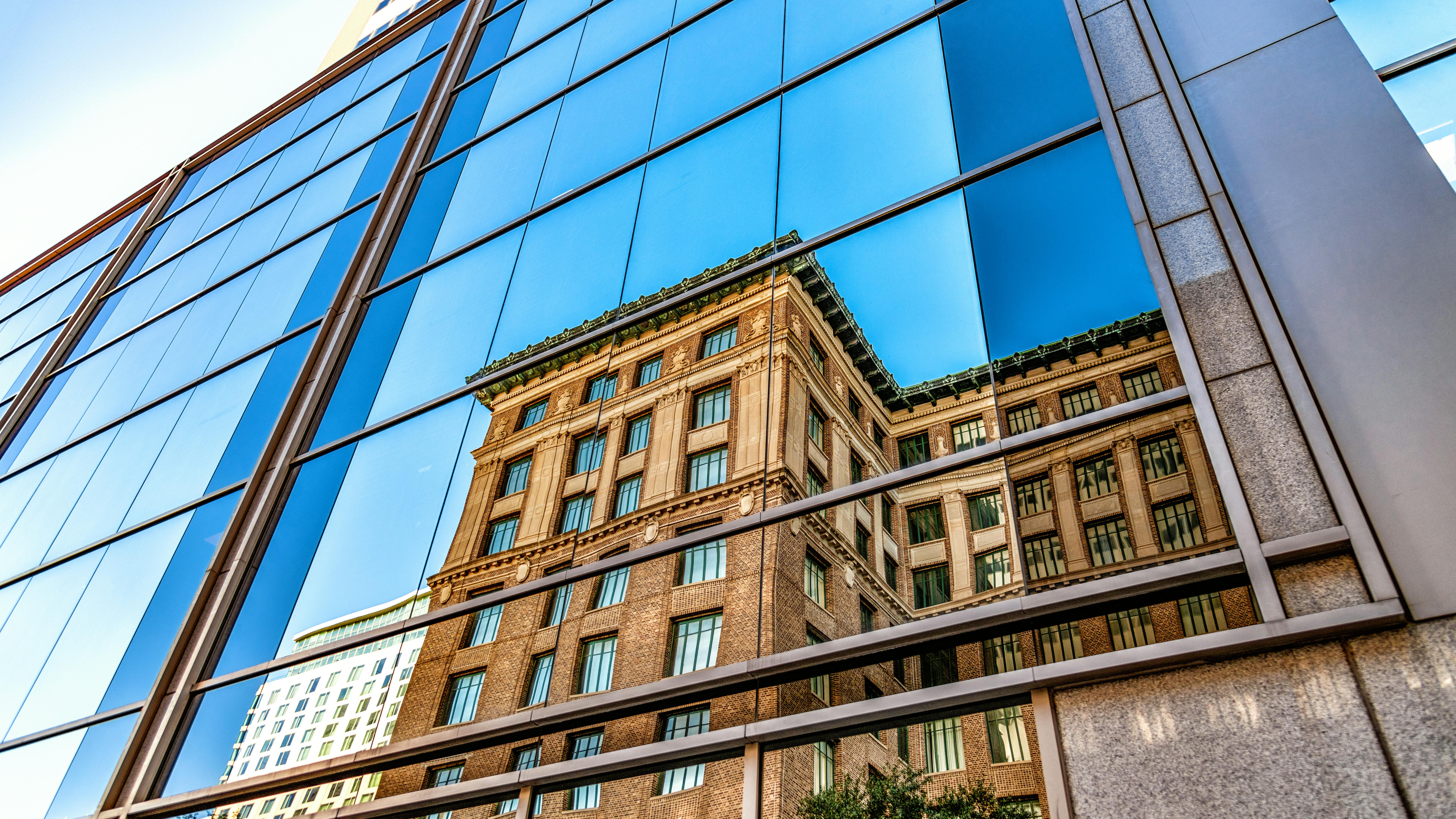 Reflection of old brick building in glass of new modern building.