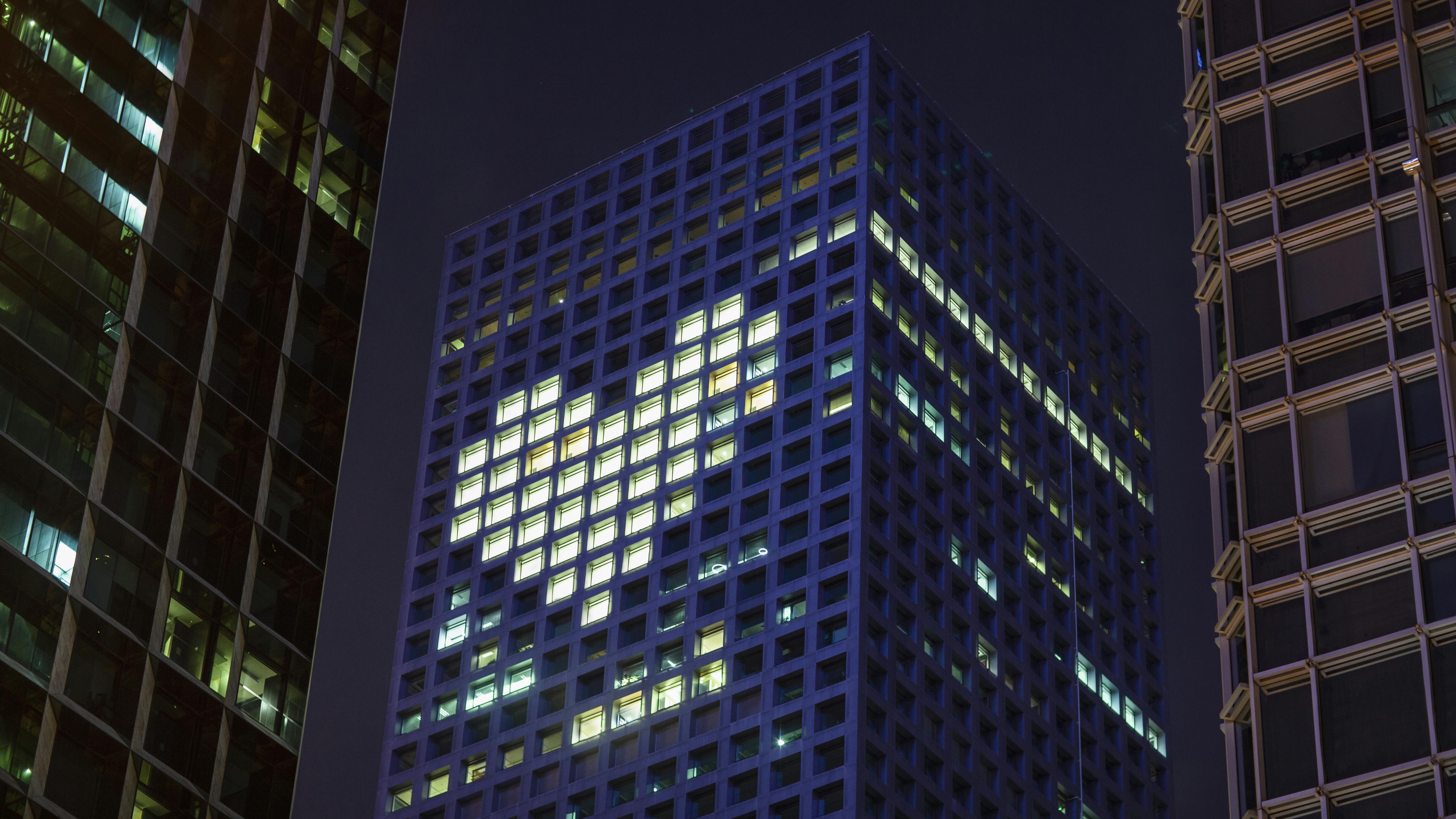 Commercial building at night with lights on that form the shape of a heart.