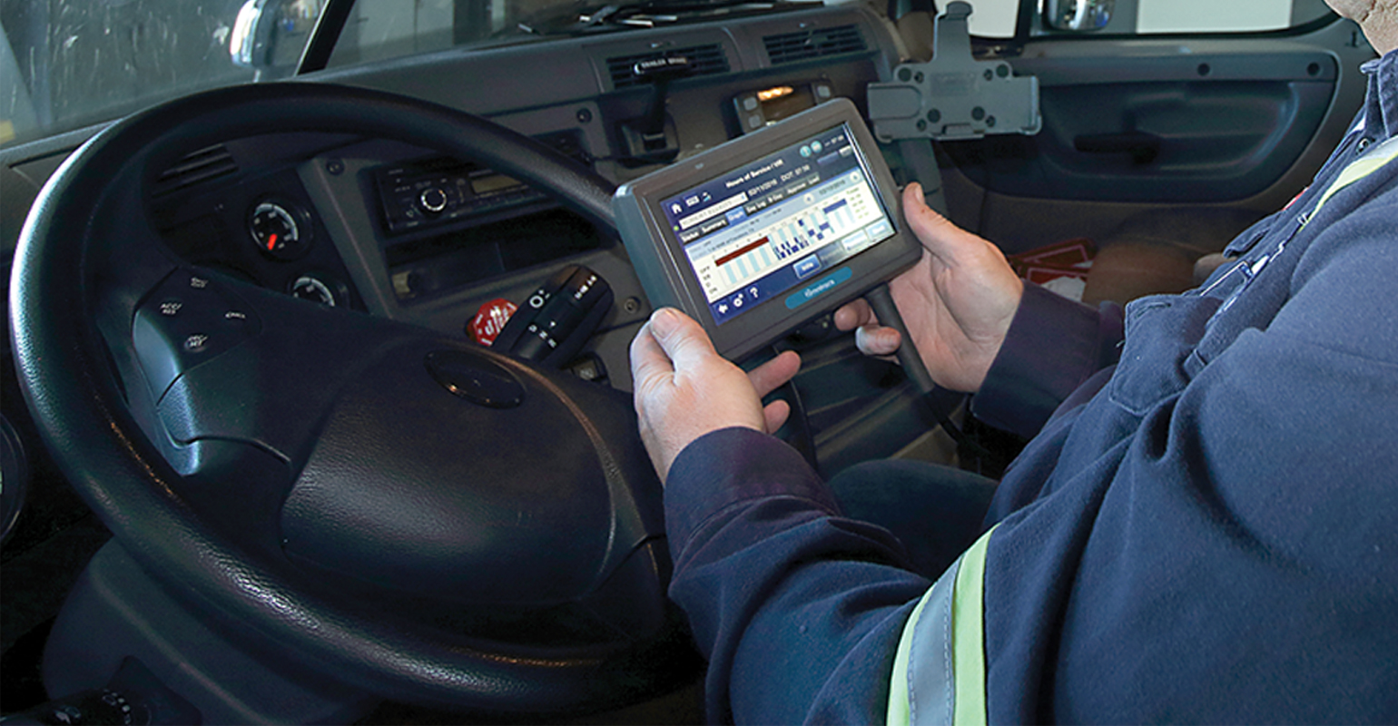 Closeup of driver holding ELD in cab of truck