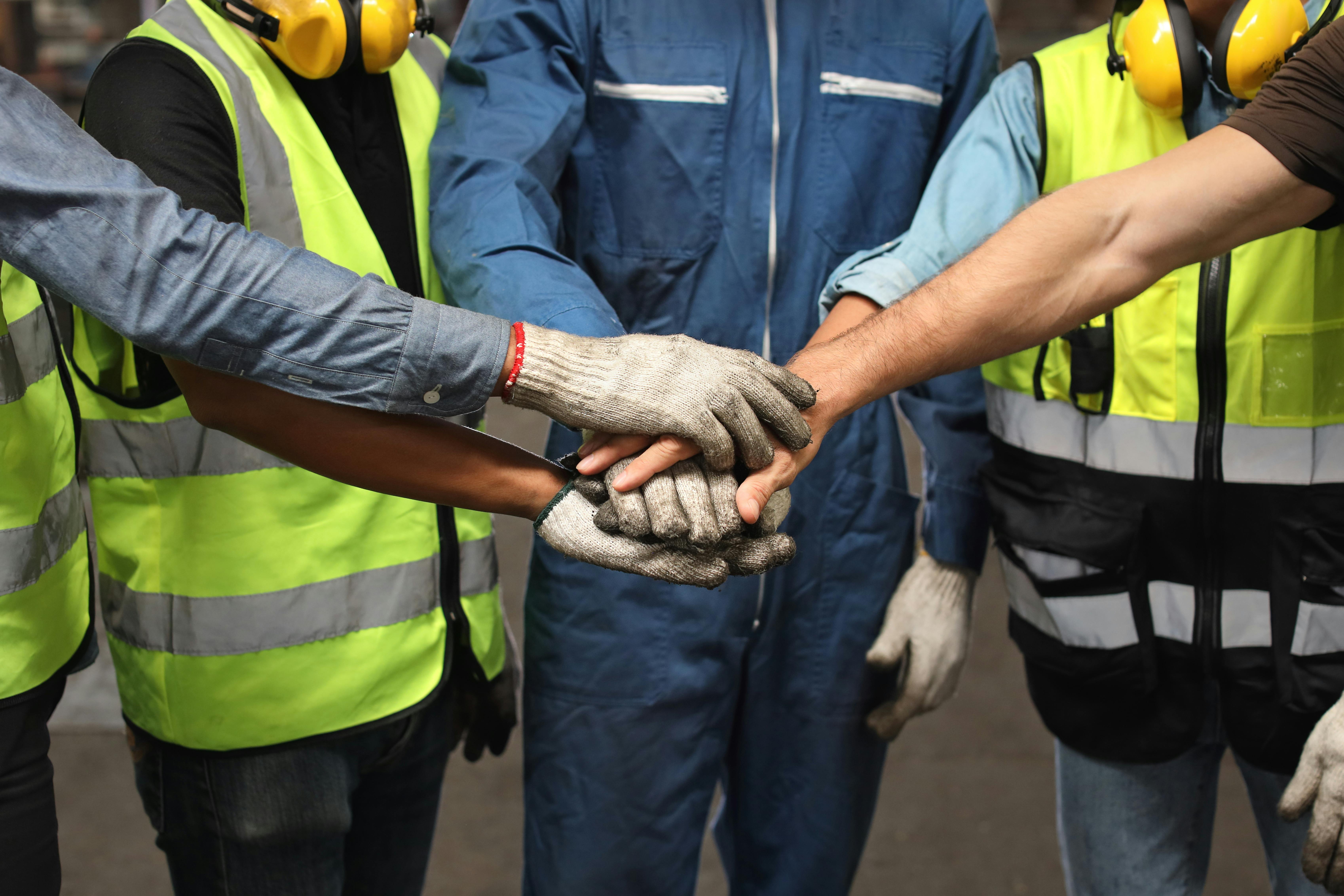 Group of technician engineer or worker in protective uniform with hardhat standing and stacking hands