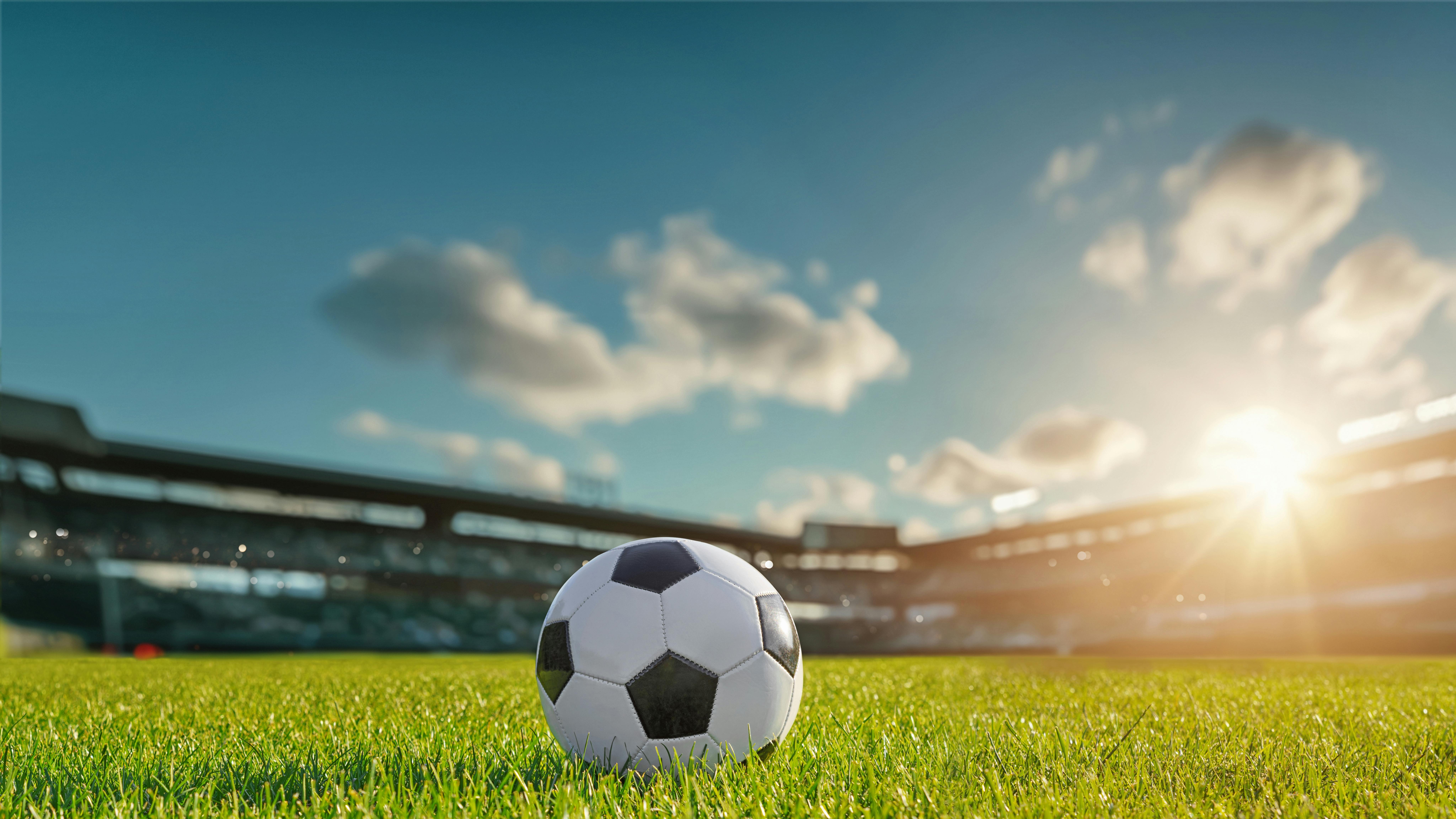 soccer field with soccer ball and sun light in background
