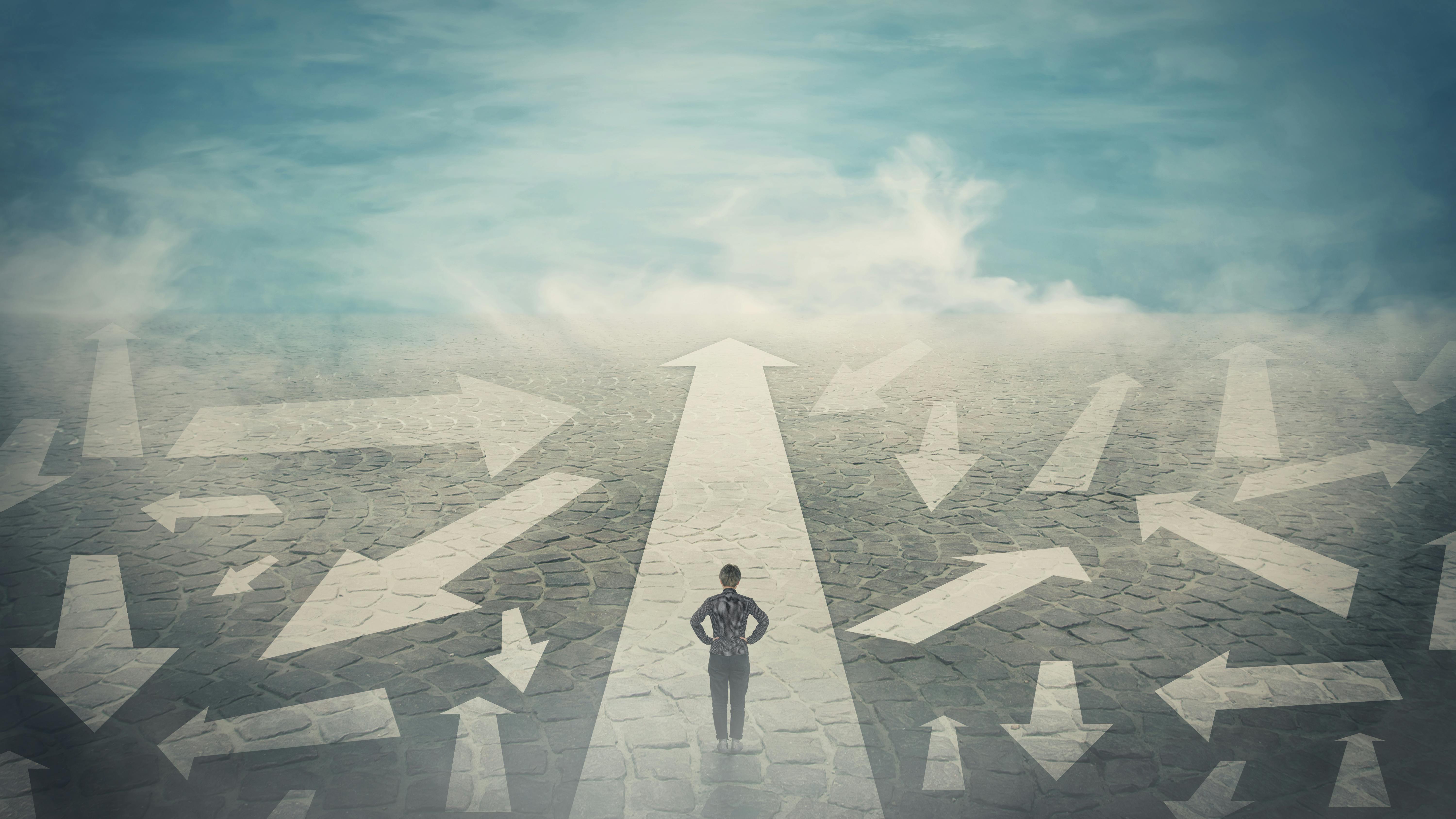 Doubtful person, hands on hips, choosing the way as multiple arrows on the road showing a mess of different directions.