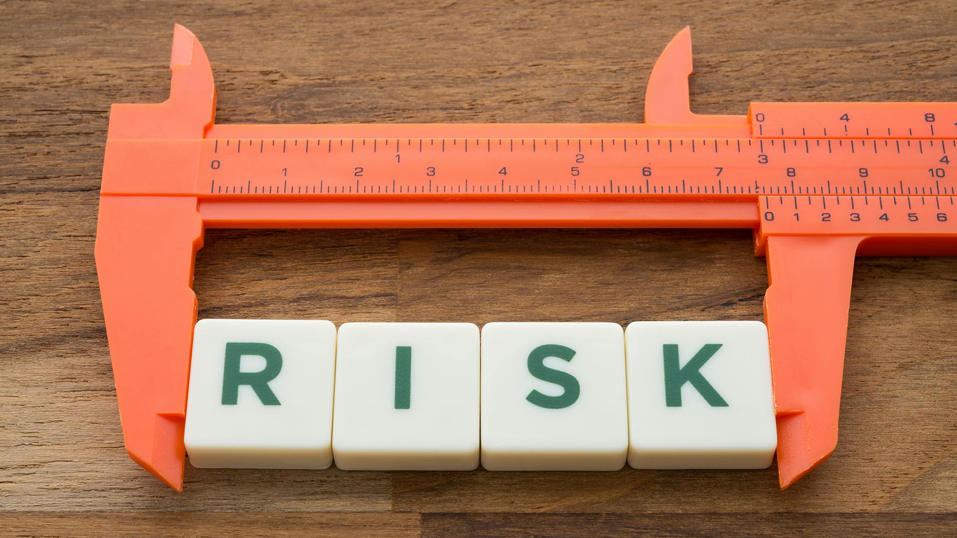 ruler measuring tile blocks with letters spelling out risk