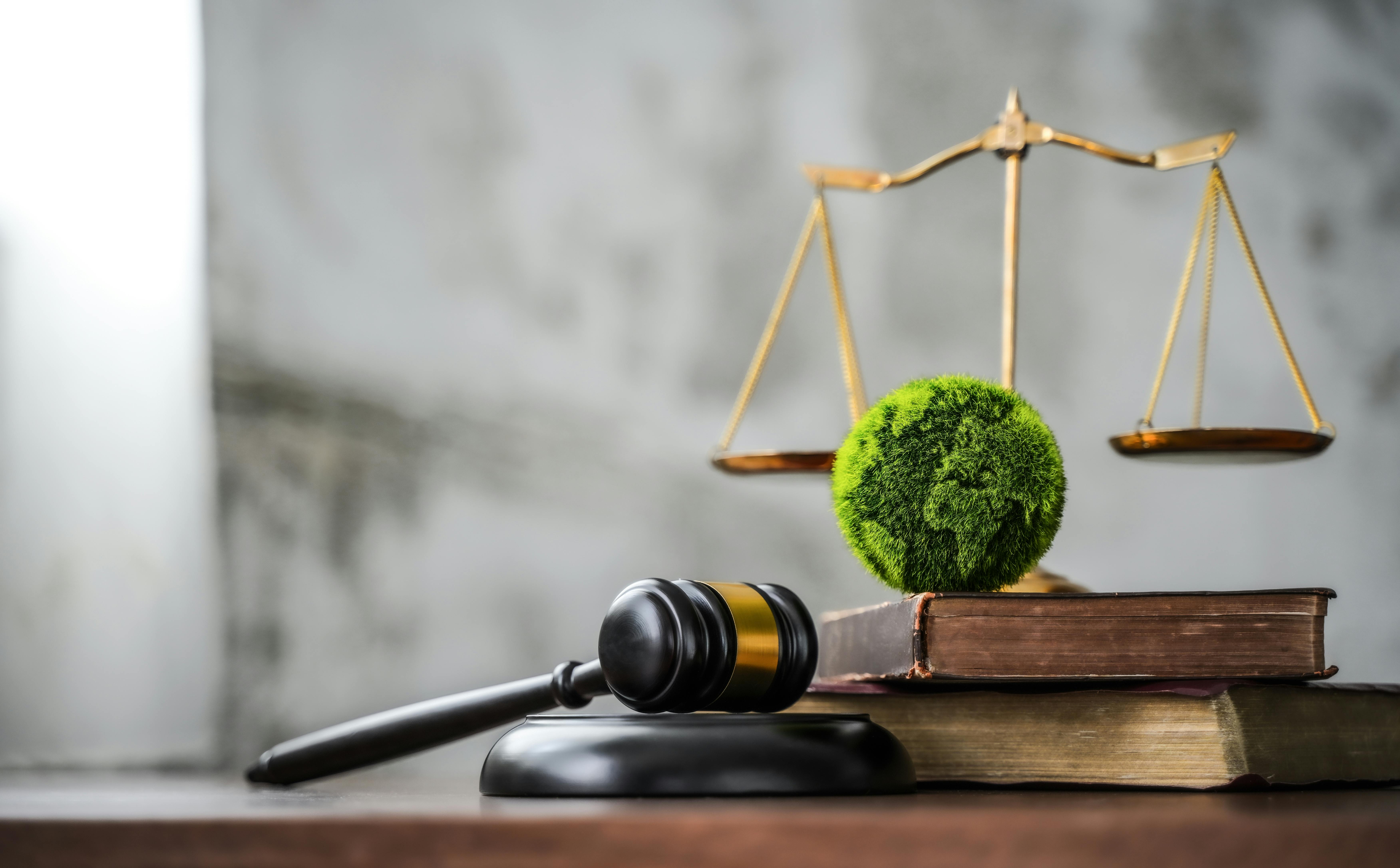 sustainable environmental regulation and laws - green globe on law books with law scale in background