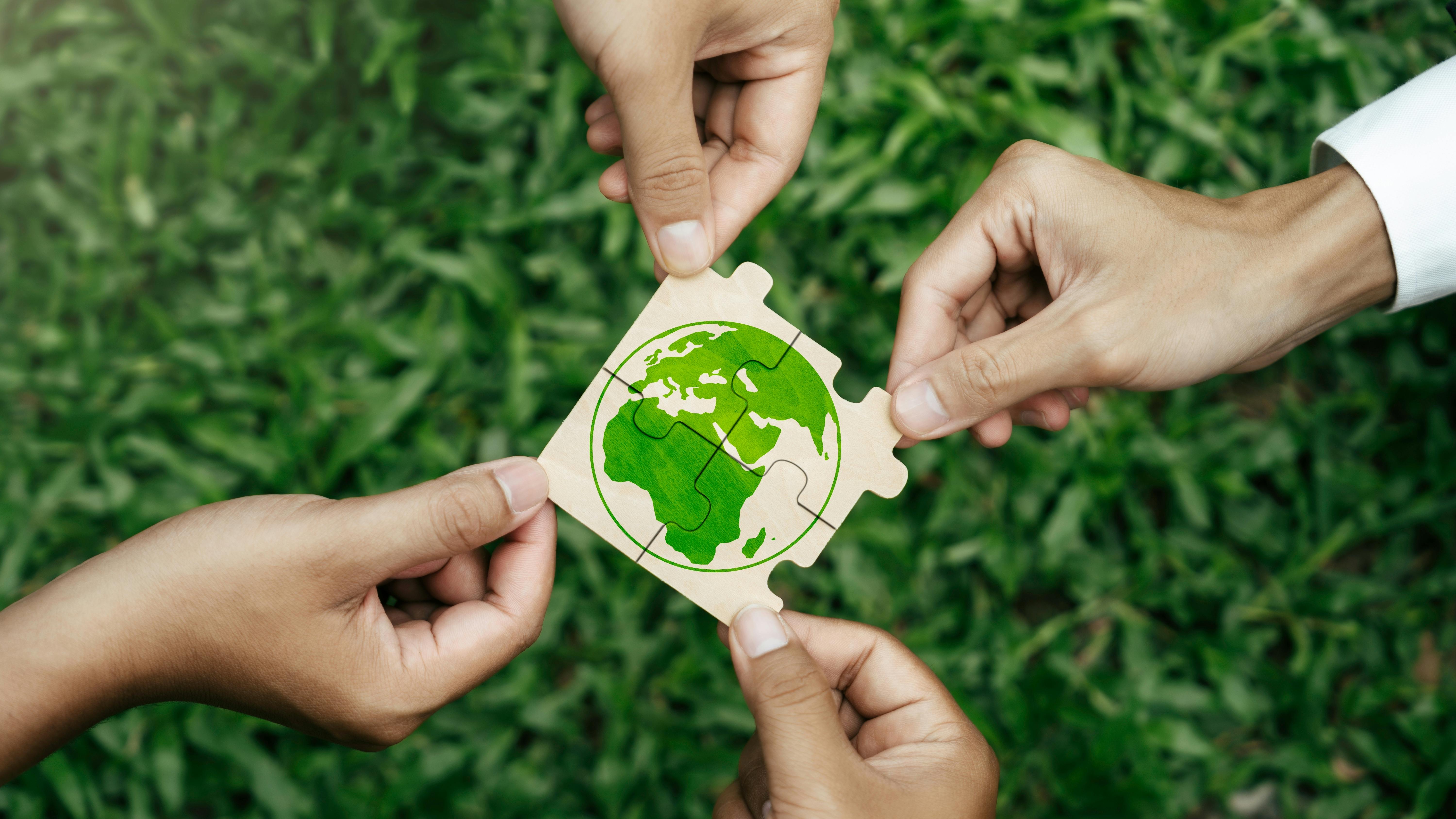 hands hold puzzle pieces that put together to show globe representing sustainability