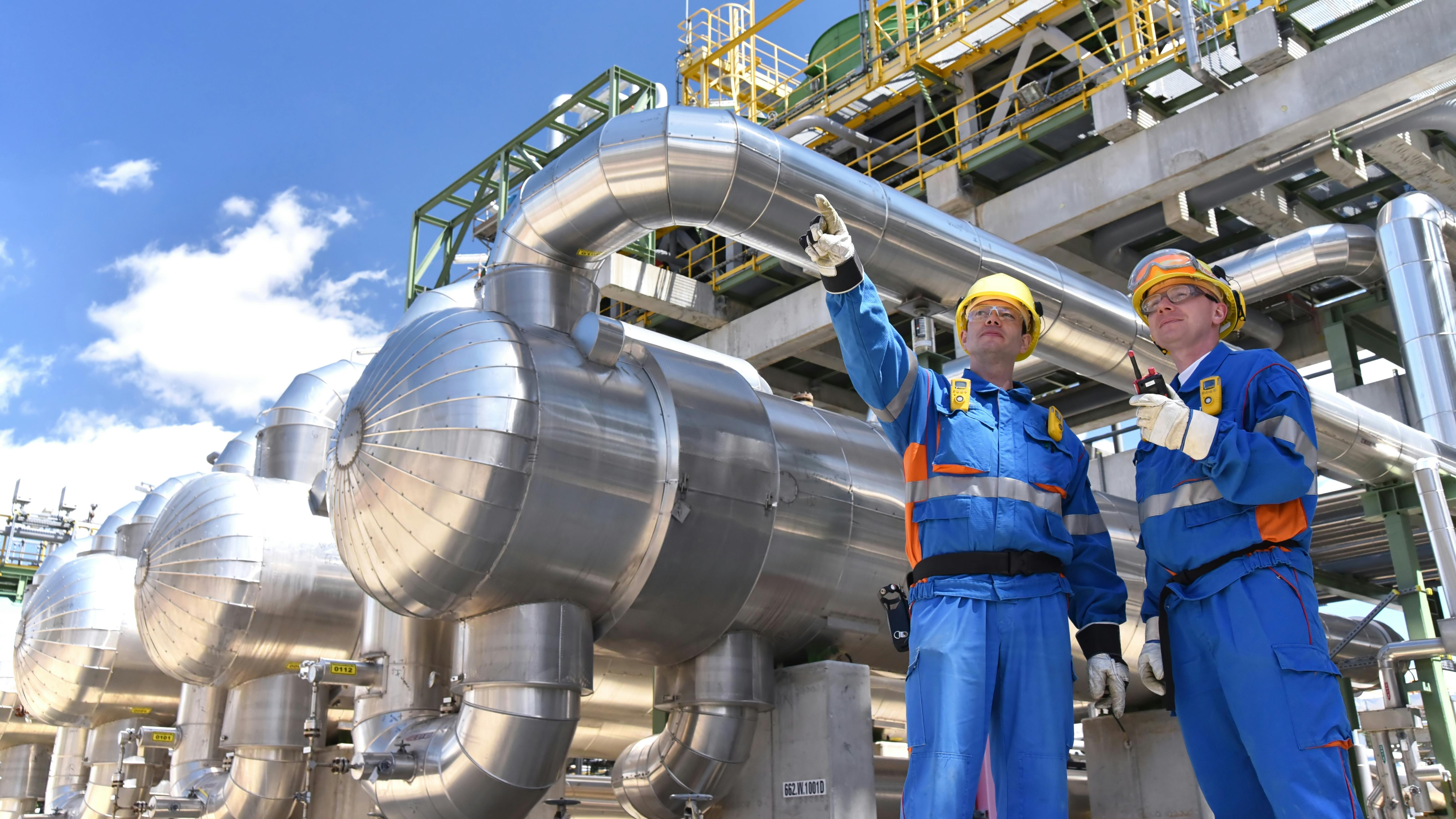 group of industrial workers in a refinery - oil processing equipment and machinery