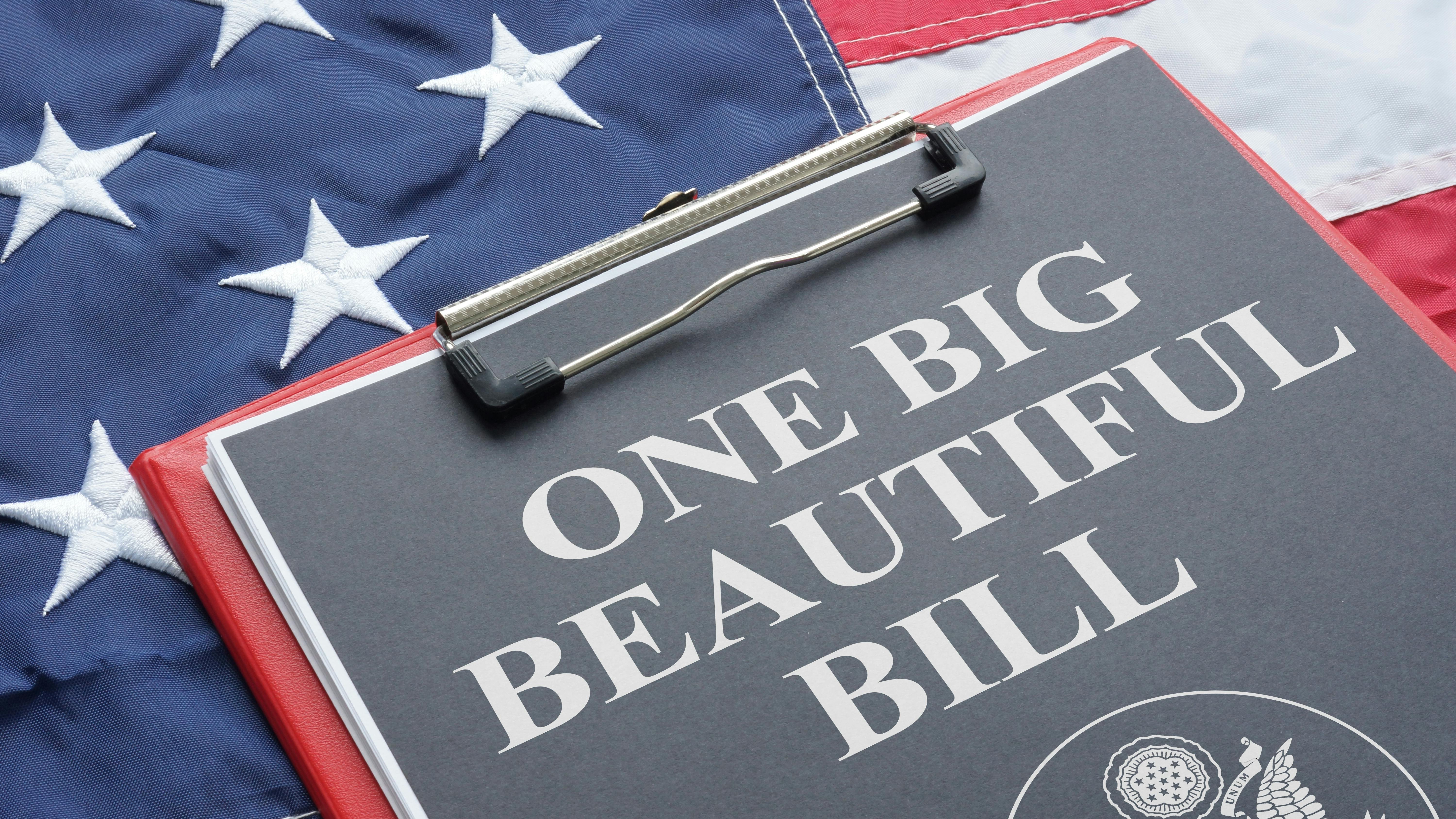 clipboard with paper reading 'One Big Beautiful Bill' sits atop American flag