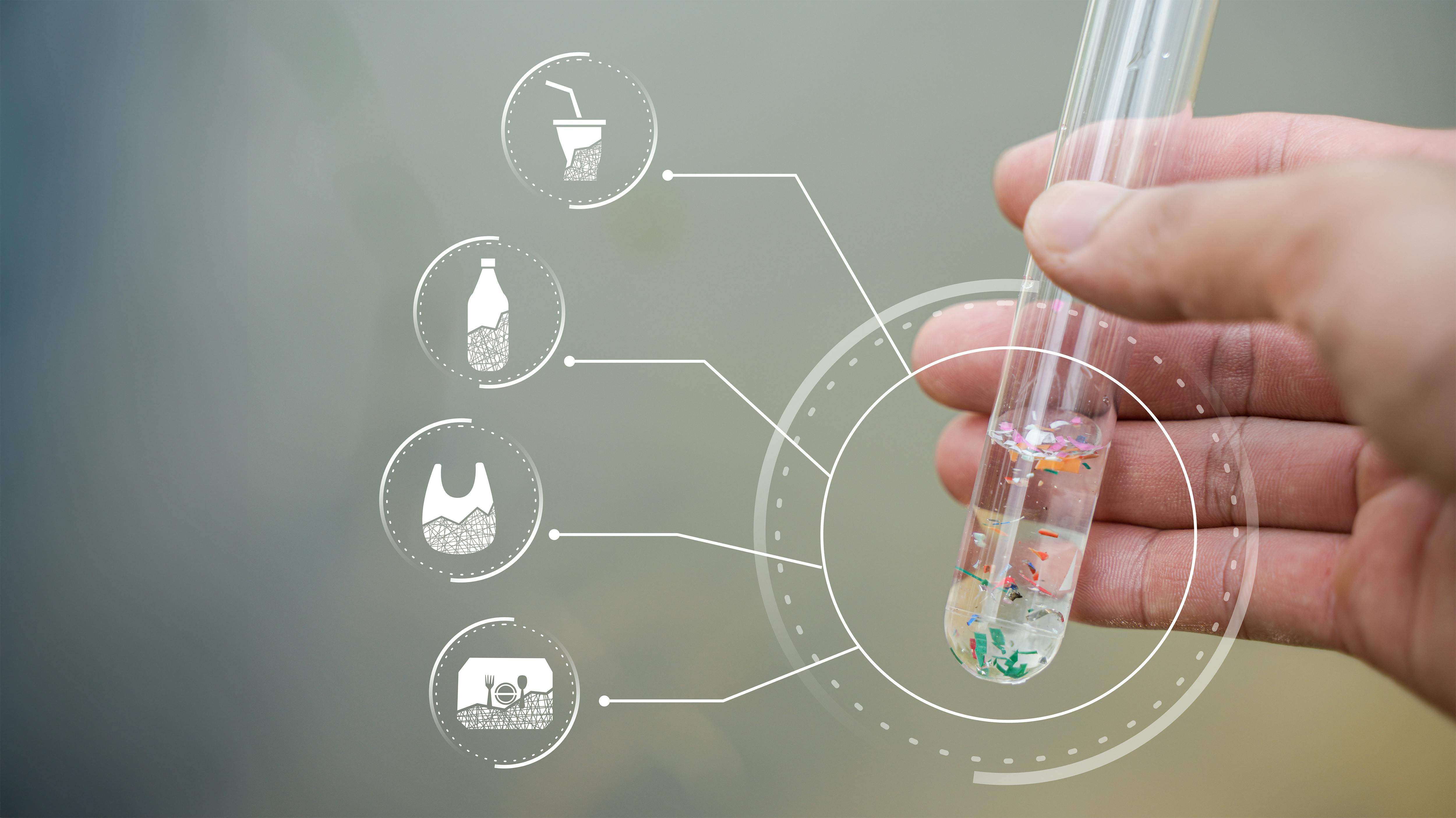 hand holds test tube filled with clear liquid and microplastics