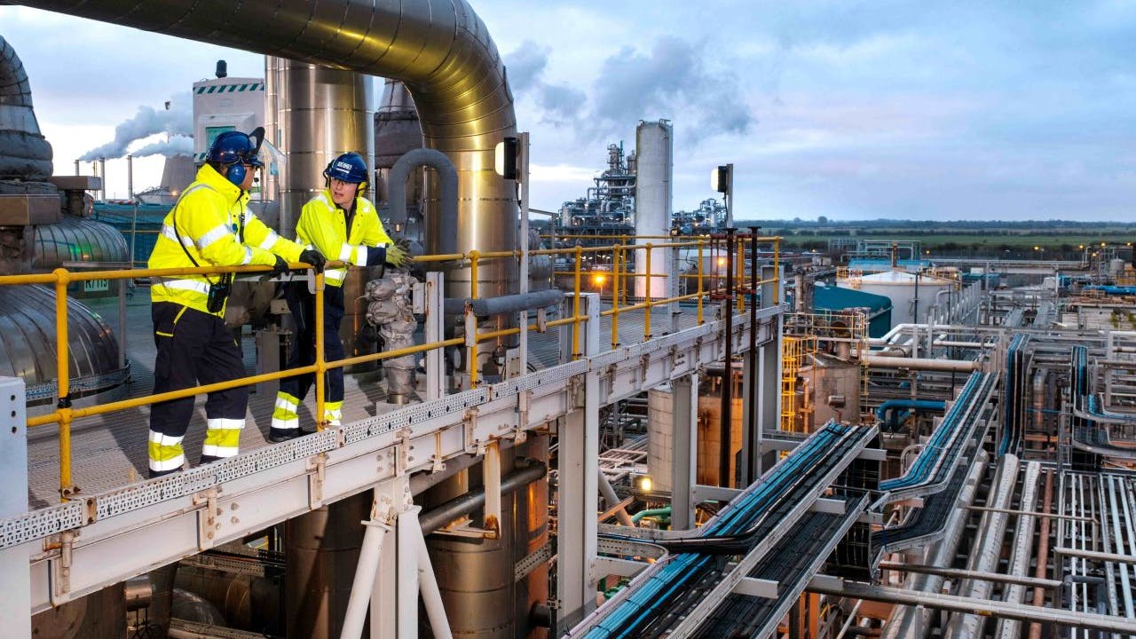 Two workers in safety gear stand on scaffold above Ineos acetyls plant in UK